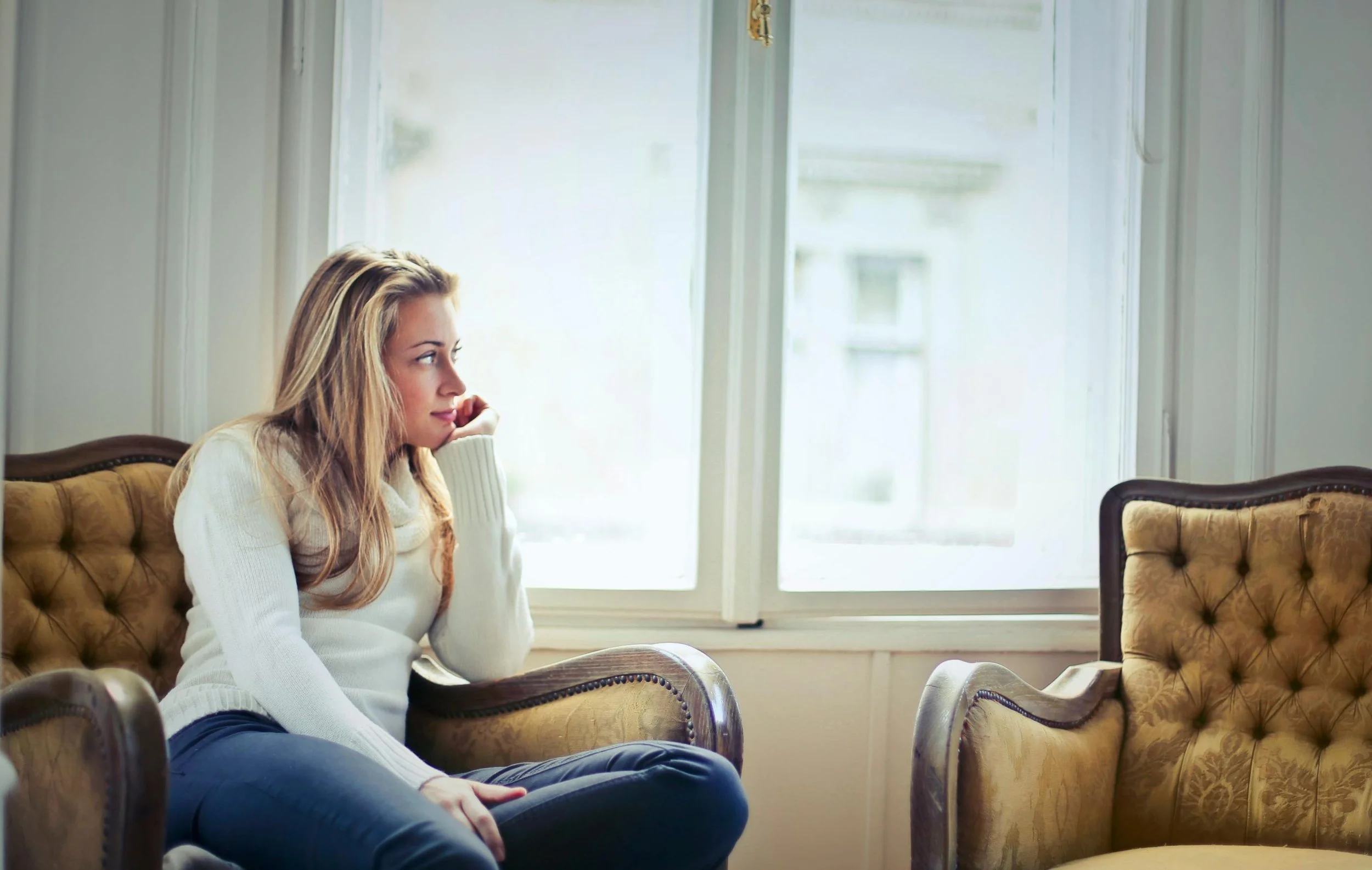 Woman seated in a vintage armchair looking out the window, OCD therapy in Connecticut