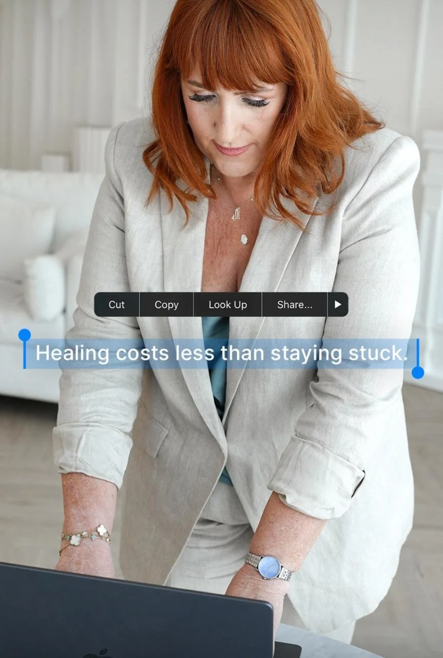 A woman with red hair in a beige suit leaning over a laptop, with a quote that says 'Healing costs less than staying stuck.'