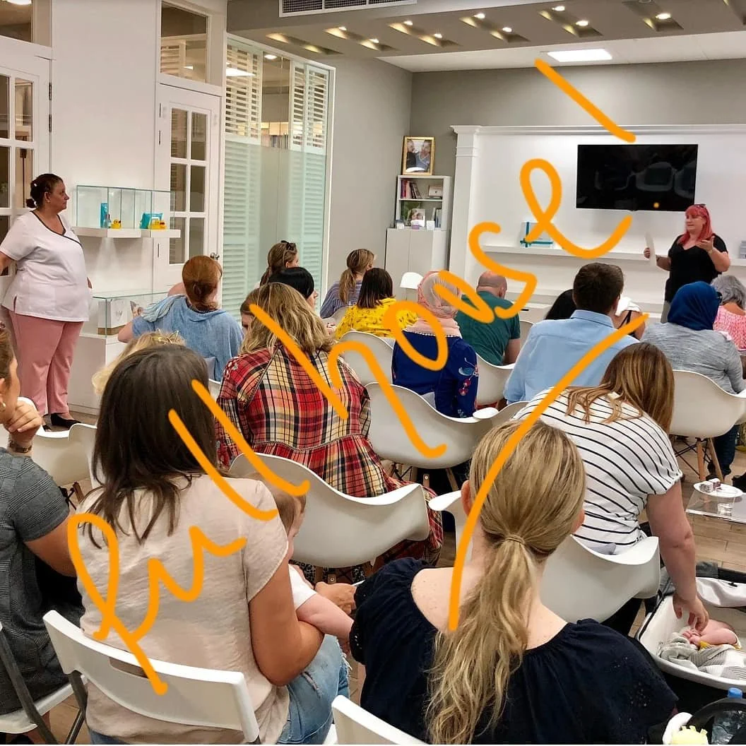 A room full of people facing Anne