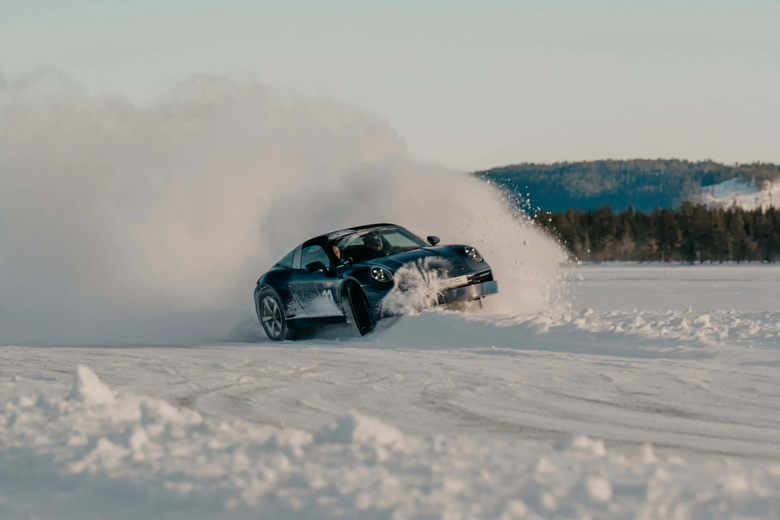 Porsche going of course into snowbank with large snow cloud.