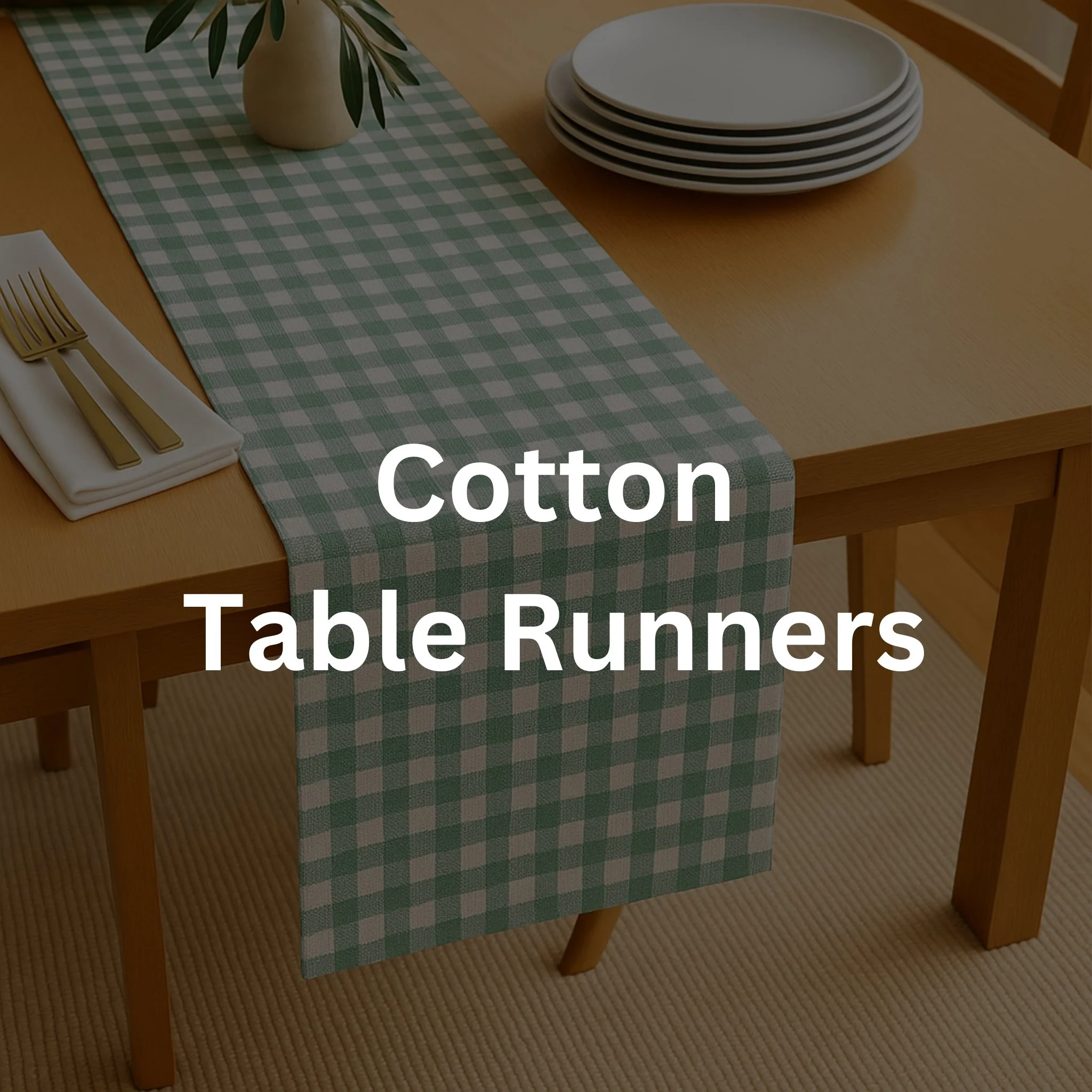 A dining table with a green and white checkered cotton table runner, a stack of six white plates, a beige vase with green leaves, and a table setting with a white napkin and gold utensils.