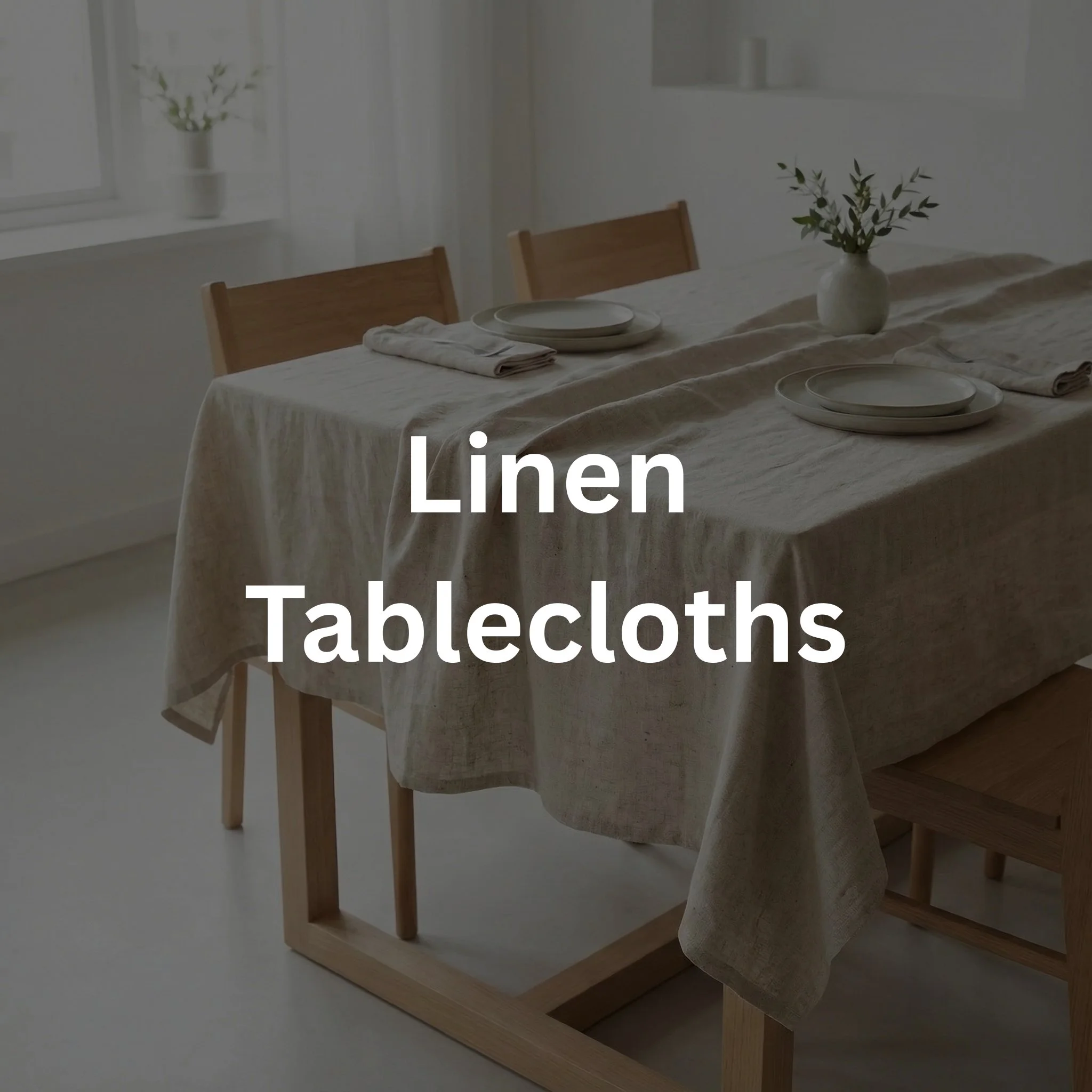 A dining table with linen tablecloth, plates, napkins, and a vase with greenery, in a bright room with a window