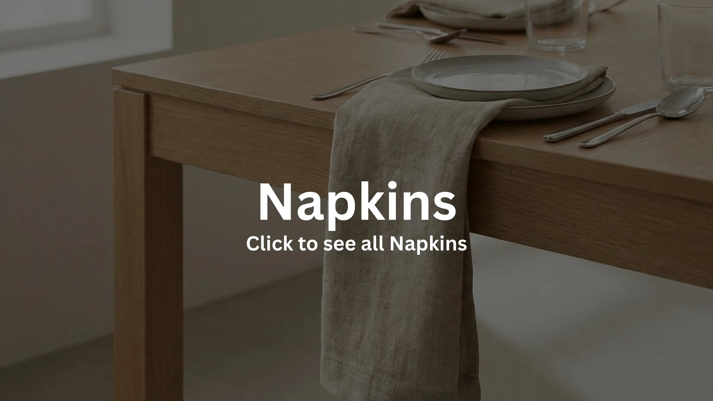 A wooden dining table set with plates, silverware, and glasses, with a napkin hanging over the edge of the table.