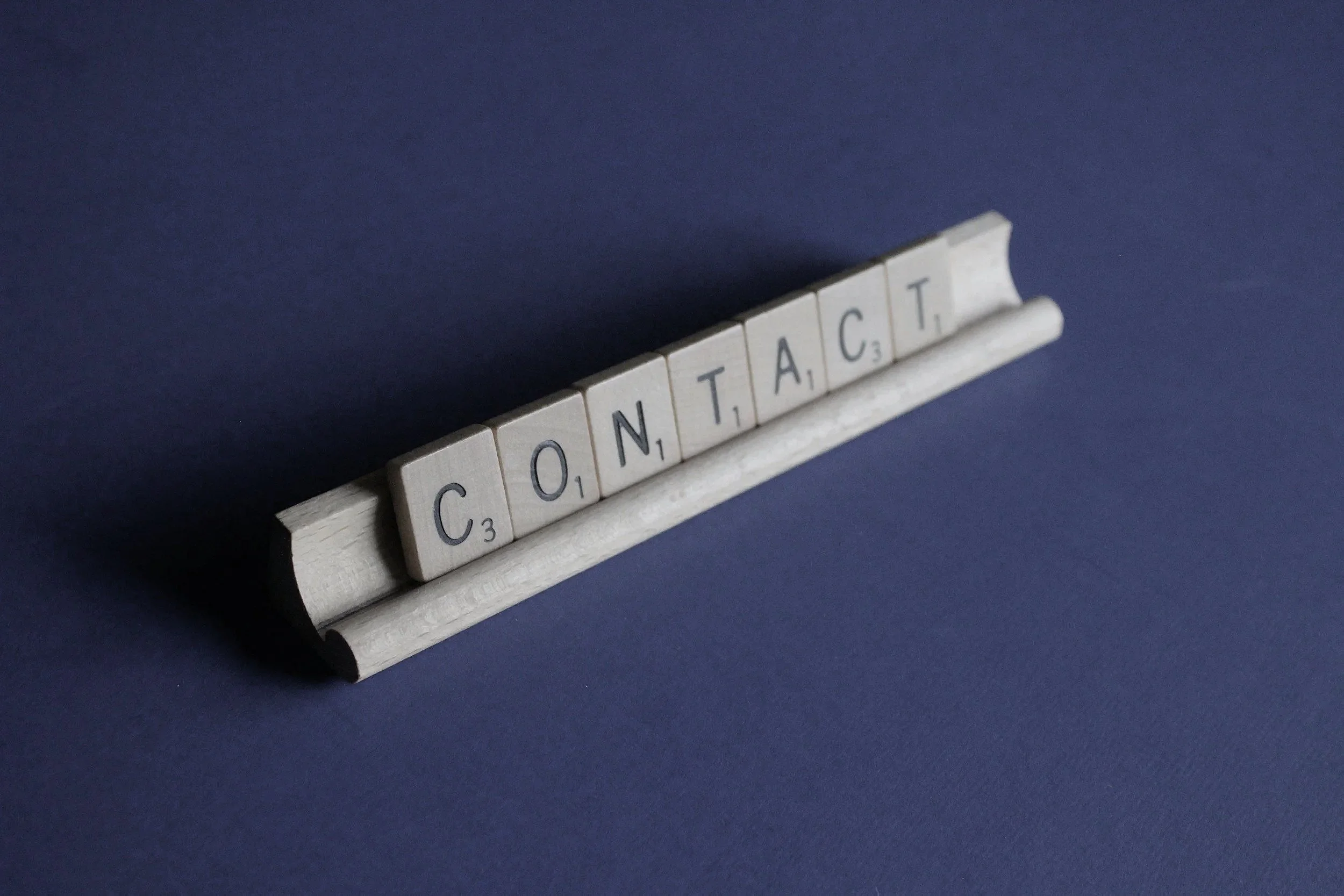 Scrabble tiles spelling out the word 'CONTRAST' on a blue background.