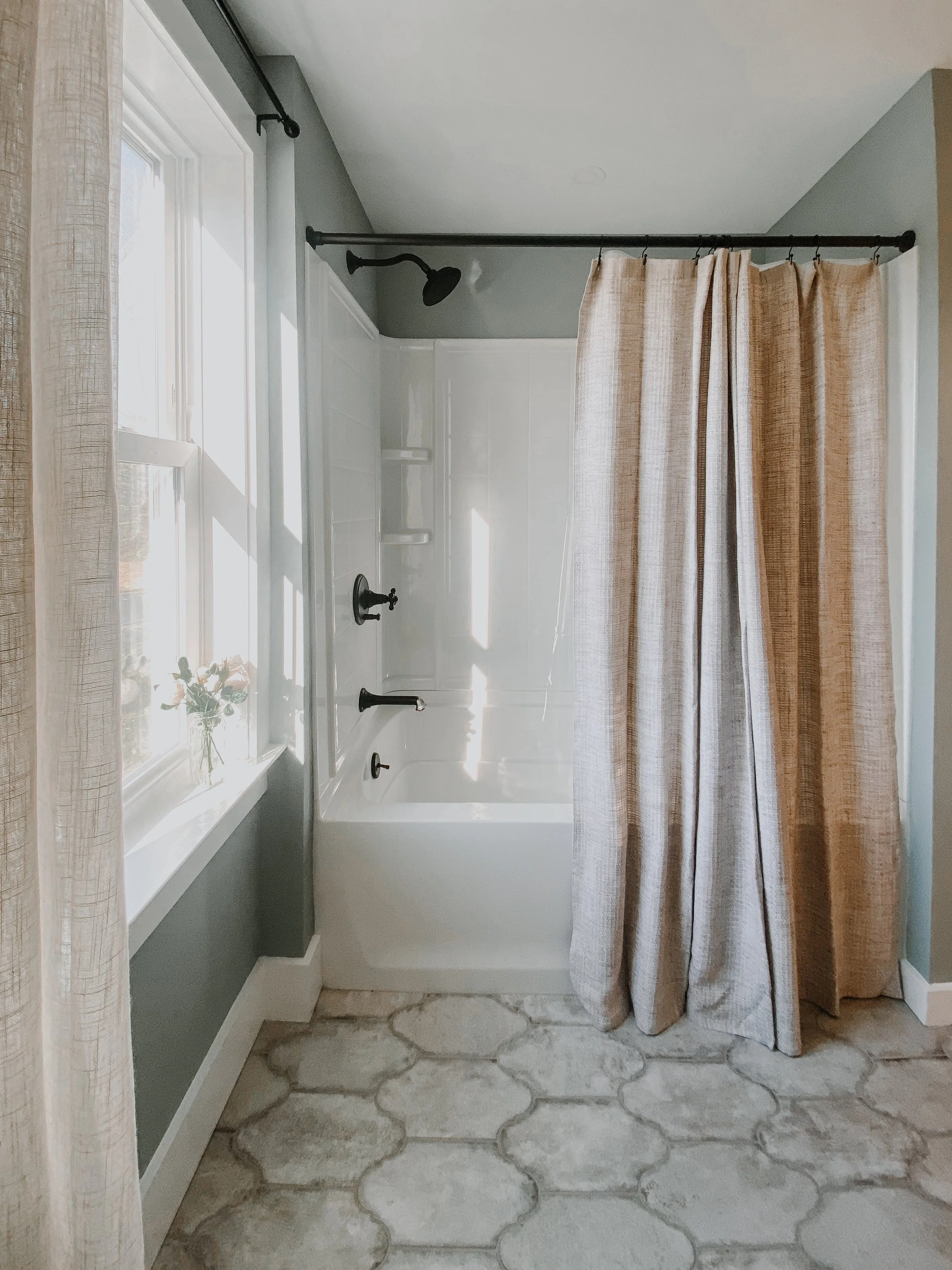 rustic modern farmhouse bathroom tile floor and shower with modern fixtures and cotton shower curtain