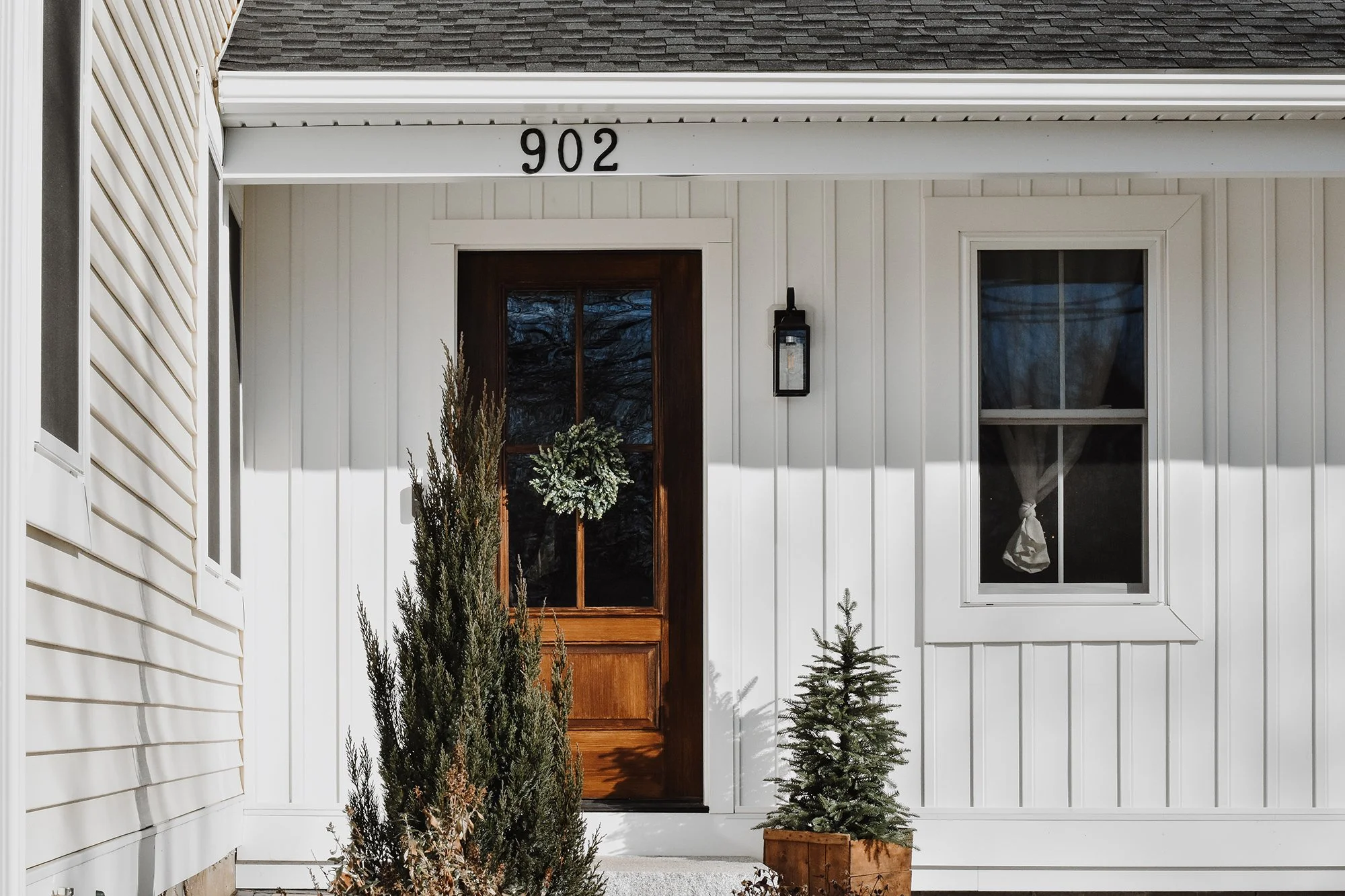1890 restored farmhouse front door entrance with white siding and green plants