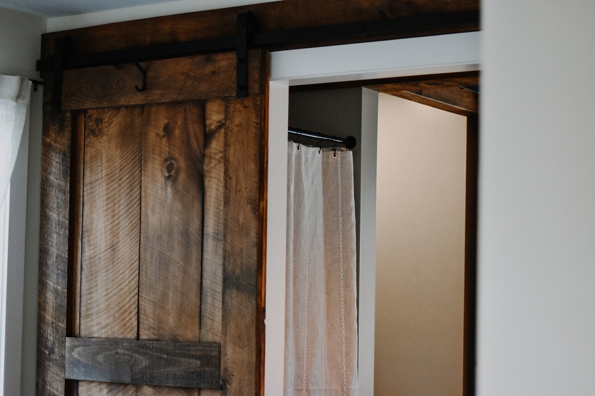 rustic modern farmhouse refurbished rustic barn door, curtain for standup shower peeking behind barn doors