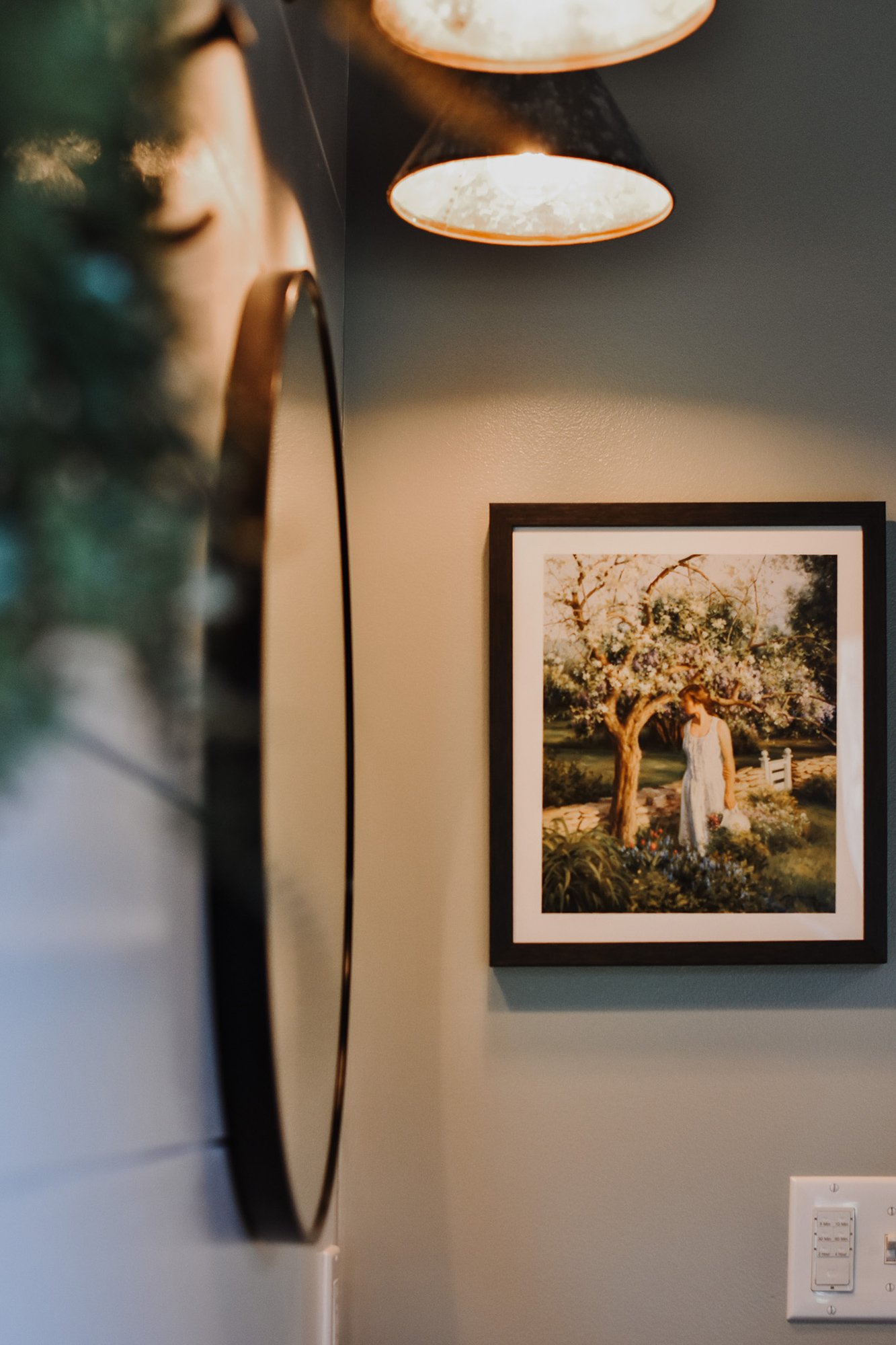 rustic modern farmhouse bathroom details,  antique wall art, round mirror, panel wall, metal cone sconce lights