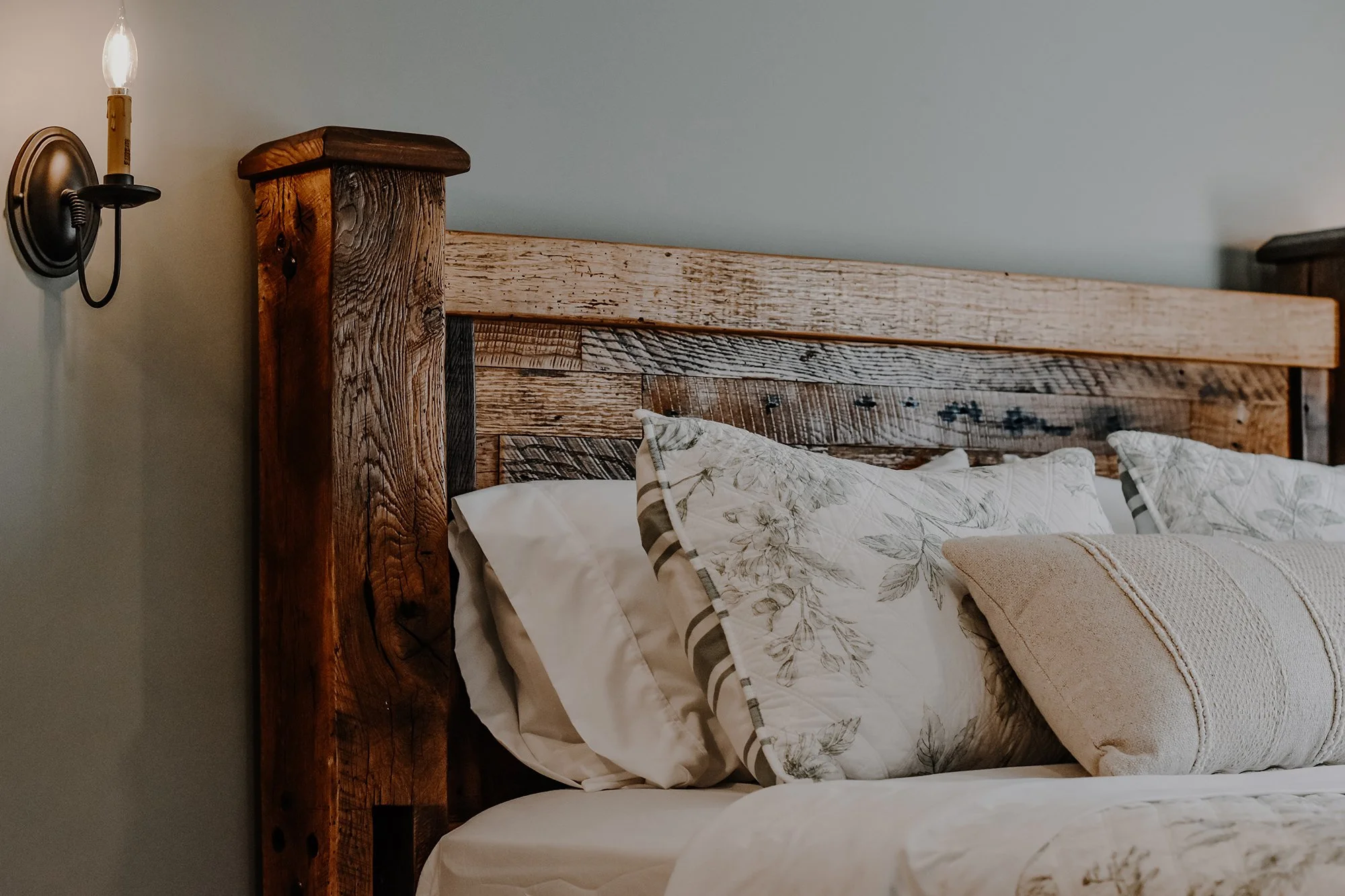 Farmhouse bedframe rrustic dark wood candlestick lights and creamy linens