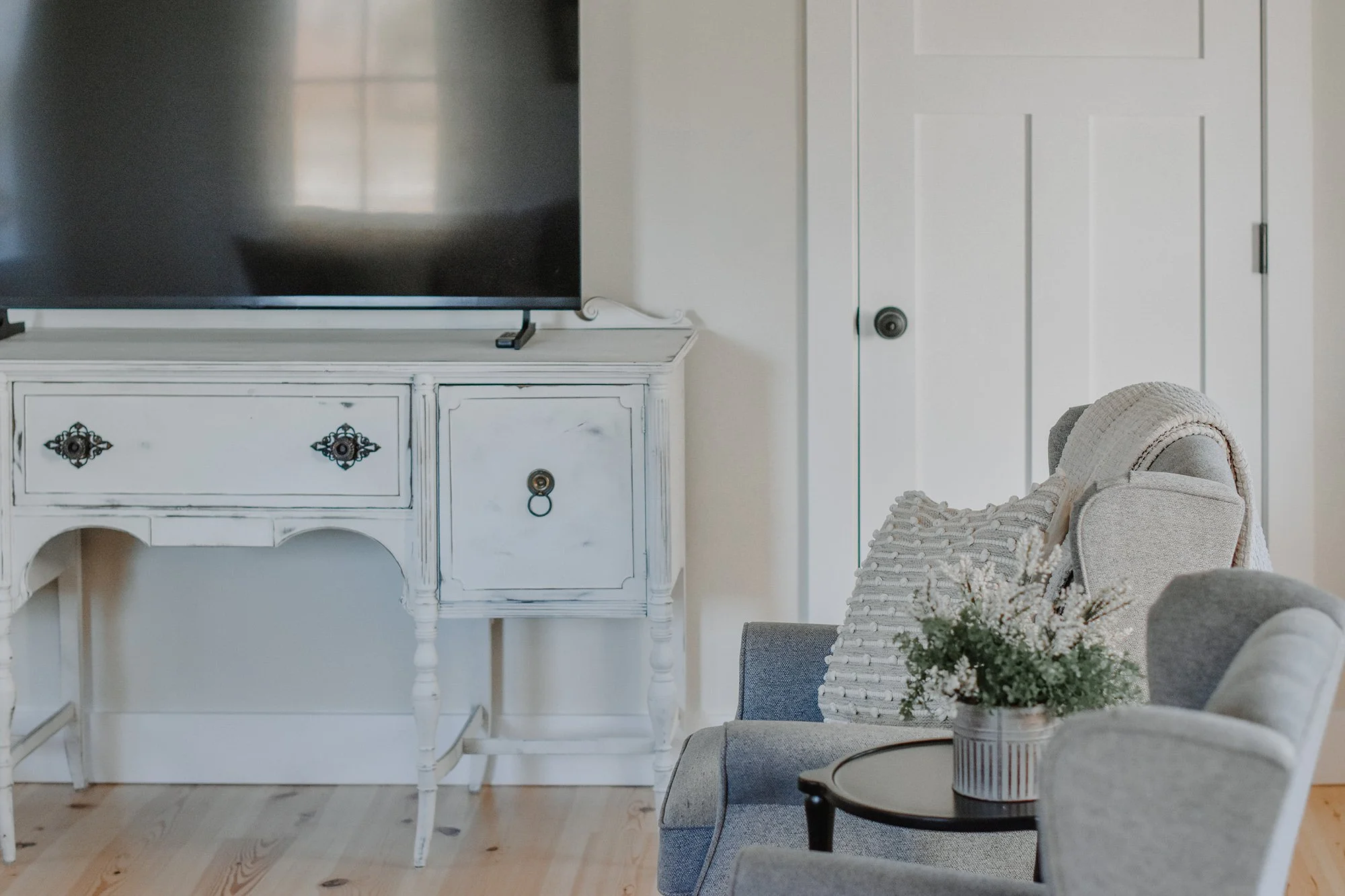 antique buffet, tv and gray sittin chairs with center coffee table and rustic plant decor in rustic farmhouse stay