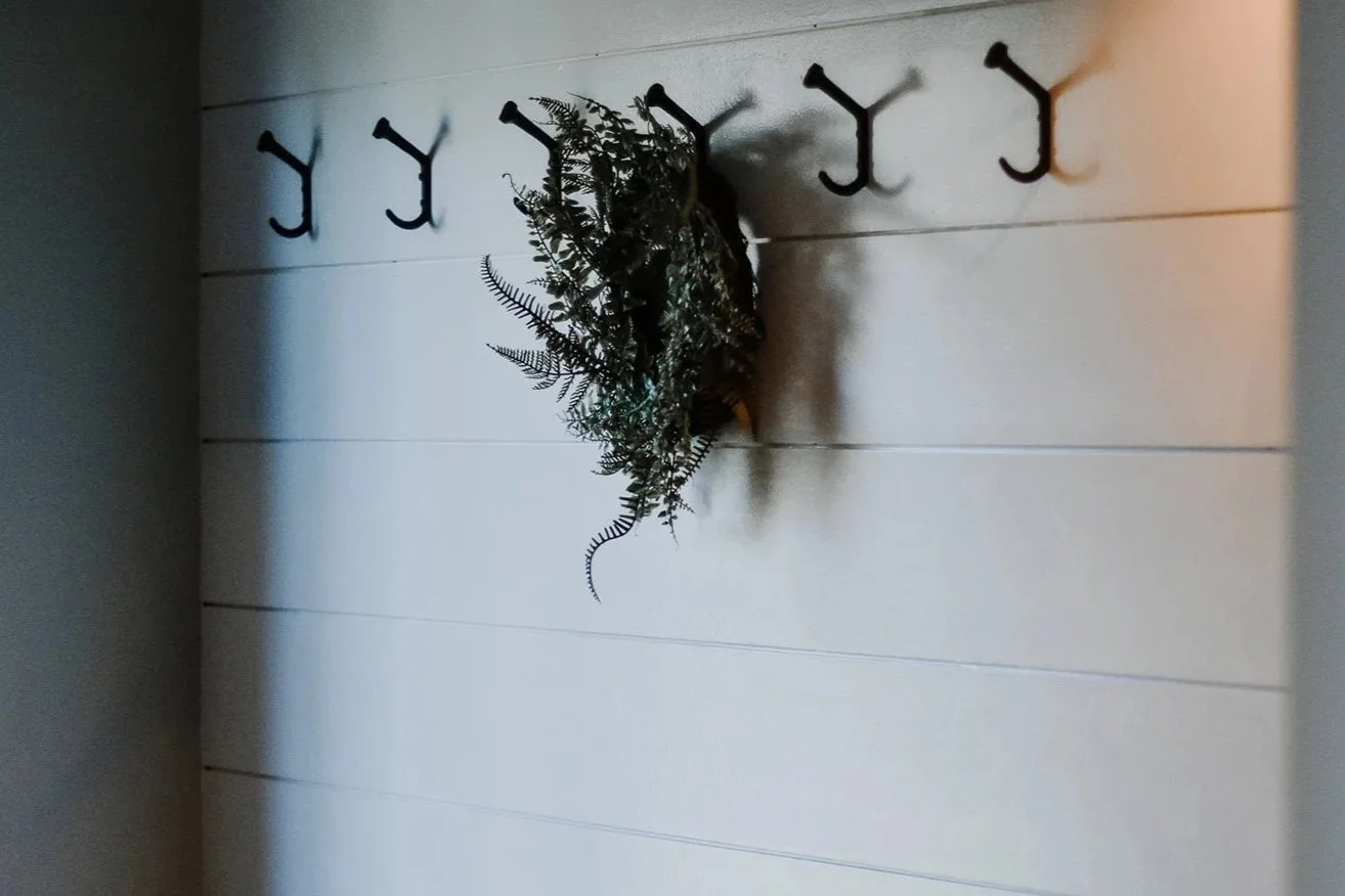 rustic modern farmhouse panel accent wall, green wreath and hanging hooks