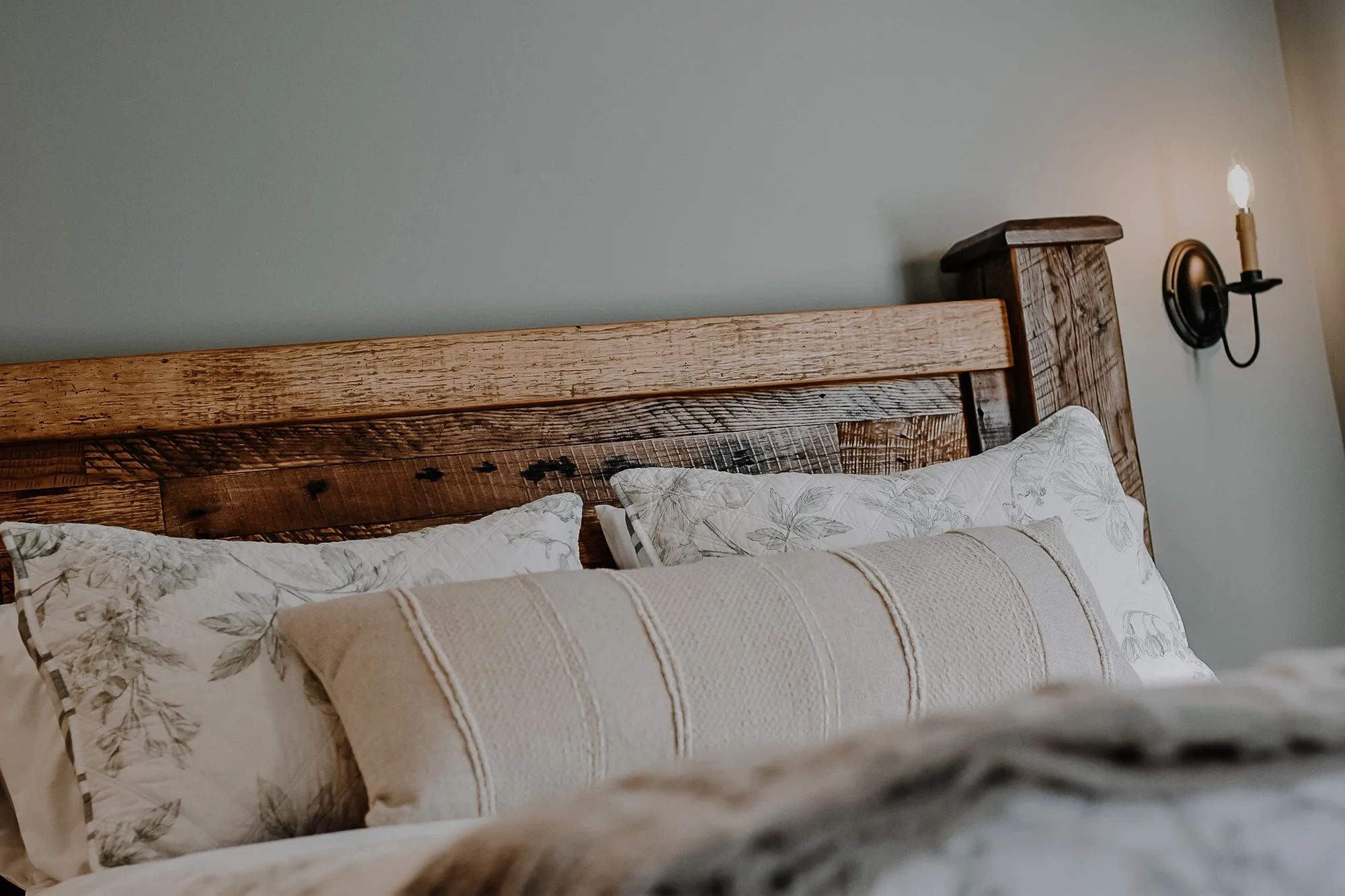 rustic handcrafted bedframe with creamy and floral linens