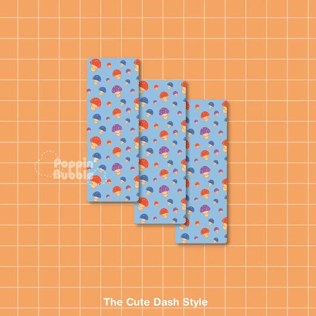 Four pieces of nail wrap with colorful mushroom patterns on a blue background, arranged on an orange grid cutting mat.