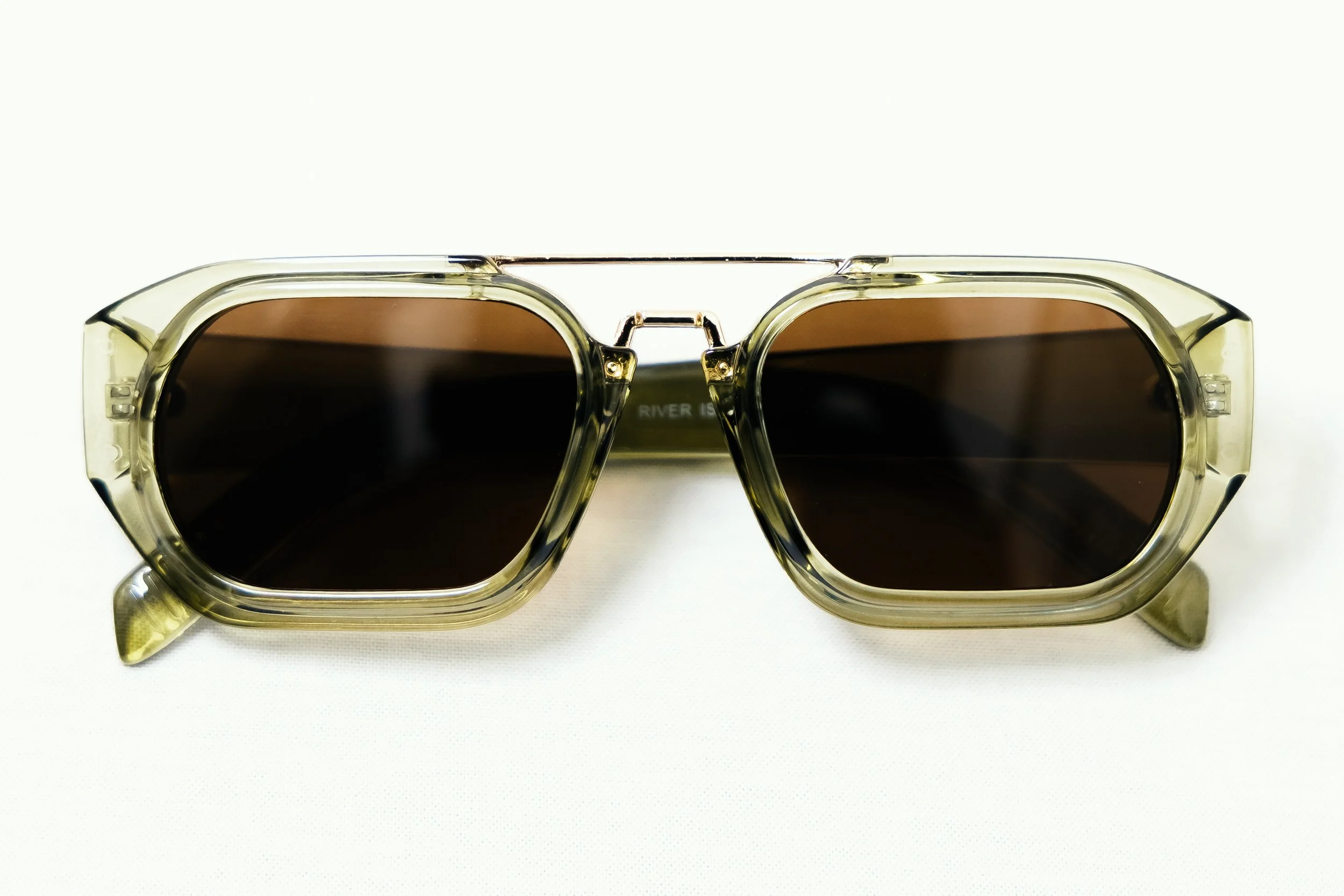 Sunglasses with dark lenses and transparent yellowish frames on a white surface.