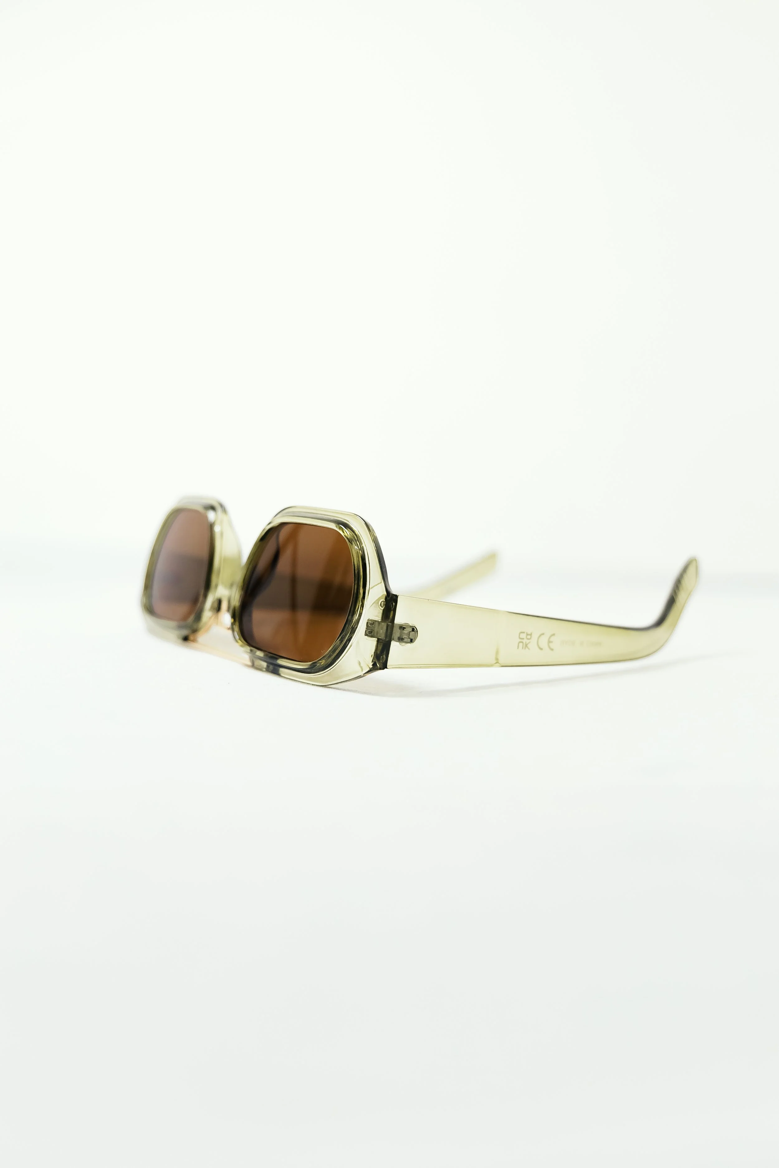 Pair of beige sunglasses with square frames and tinted lenses on a white background.