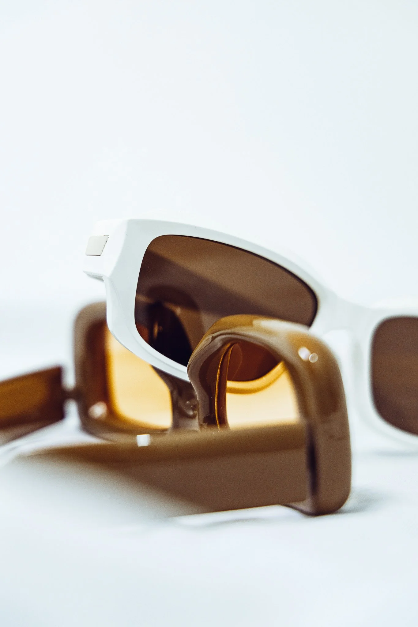 Close-up of sunglasses with white and brown frames and tinted lenses.