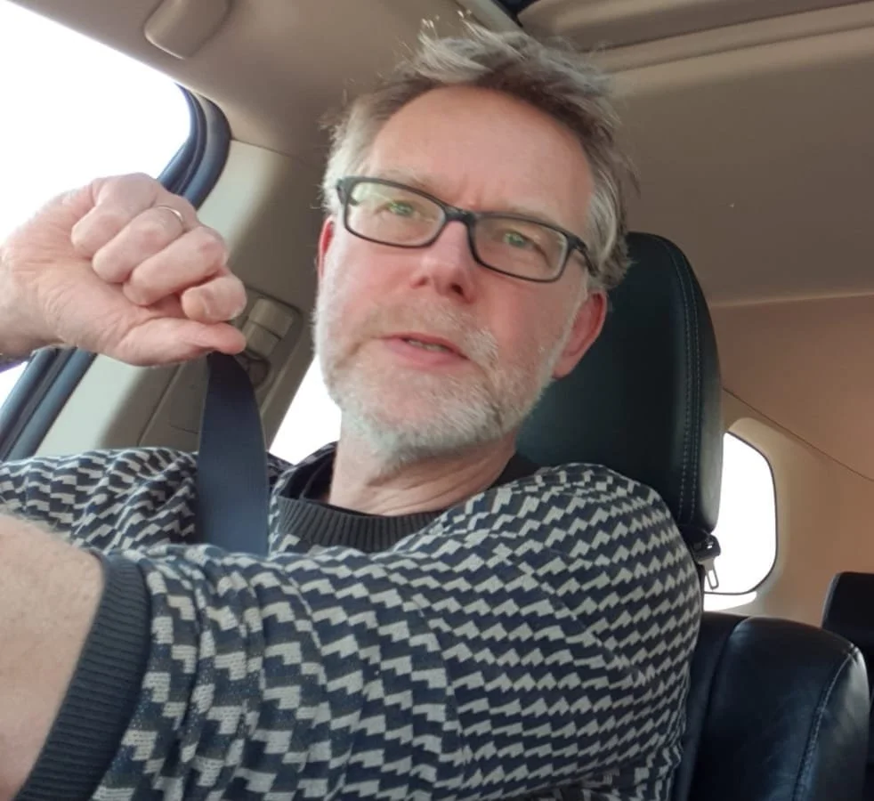 Homme avec lunettes qui ajuste sa ceinture de sécurité dans une voiture