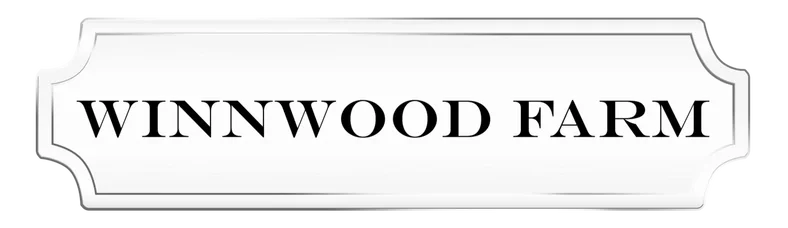Winnwood Farm sign with black text on white background and decorative border.
