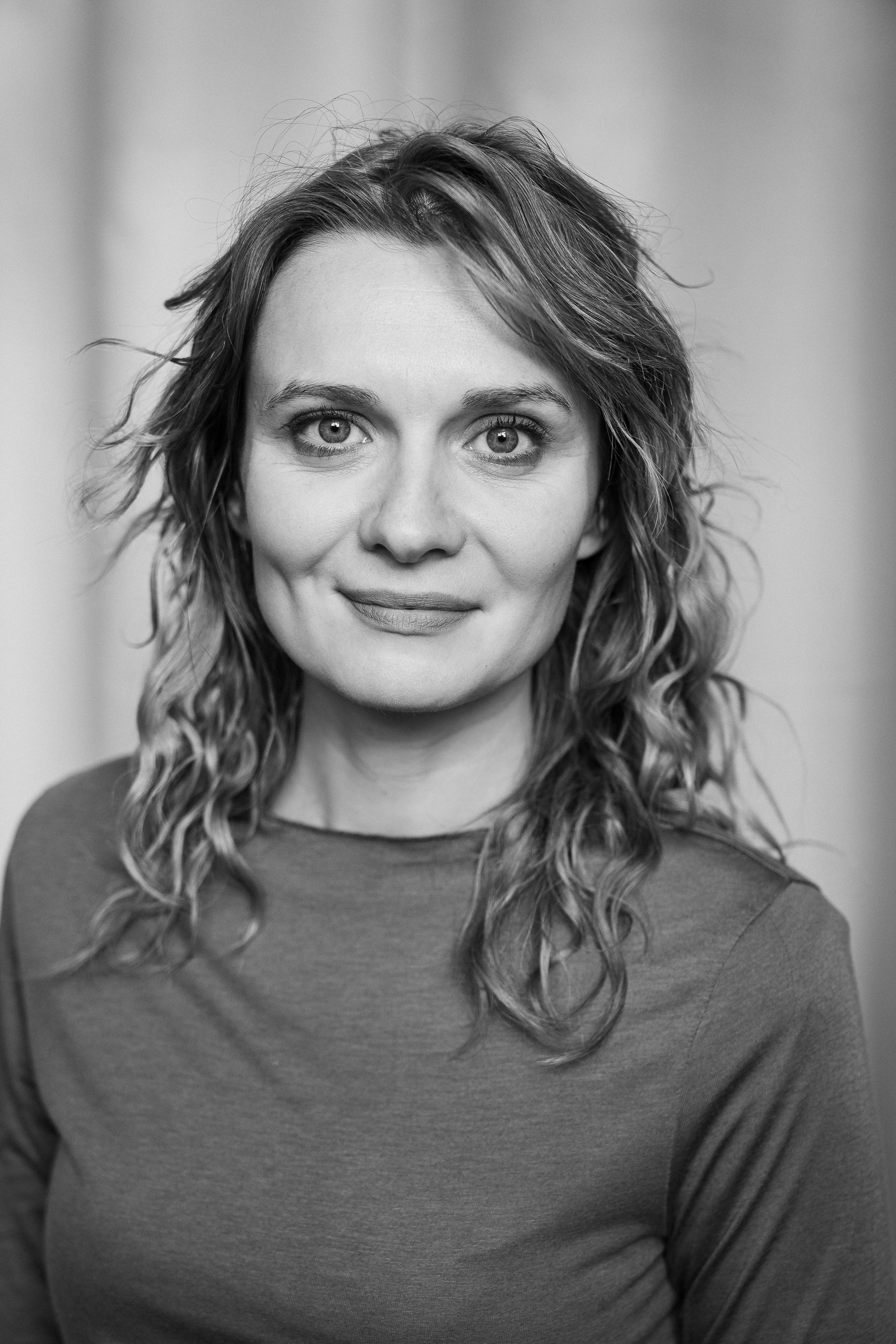 Ein Schwarz-Weiß-Porträt einer Frau mit lockigem Haar, die leicht lächelt.