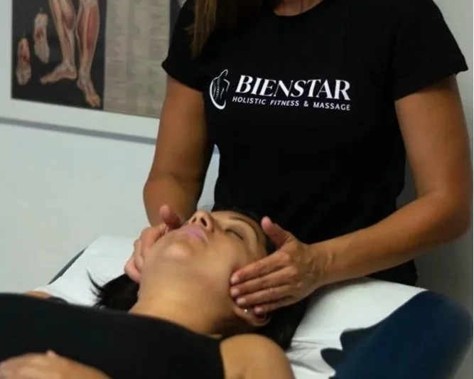A woman receiving a massage on her face from a massage therapist at Bienstar Holistic Fitness & Massage clinic.