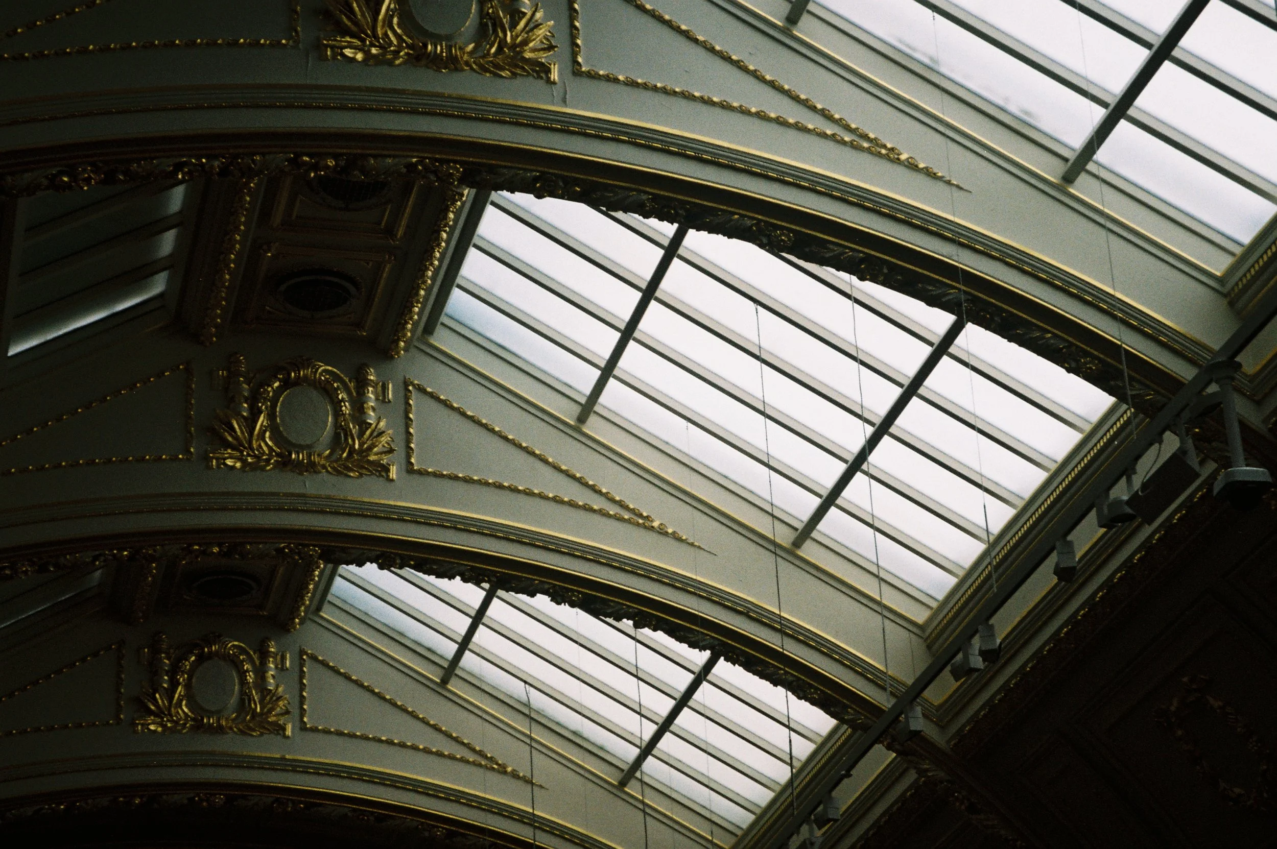 Elegant ceiling with gold embellishments and large glass skylights.