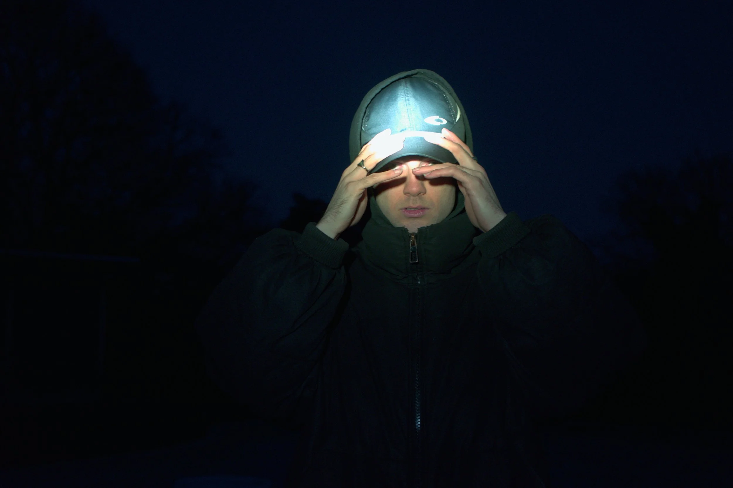 Person in dark clothing adjusting a headlamp at night.