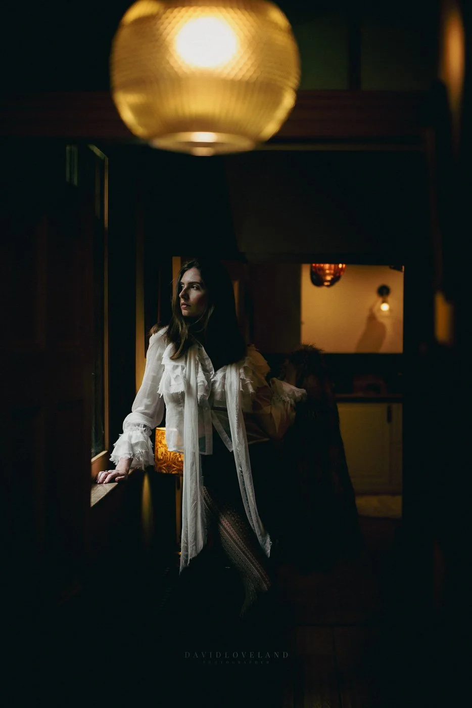 Tall model in editorial fashion shoot. Opulent Georgian house wearing dark brown pantyhose and cream ruffled blouse, David Loveland Fashion Photography