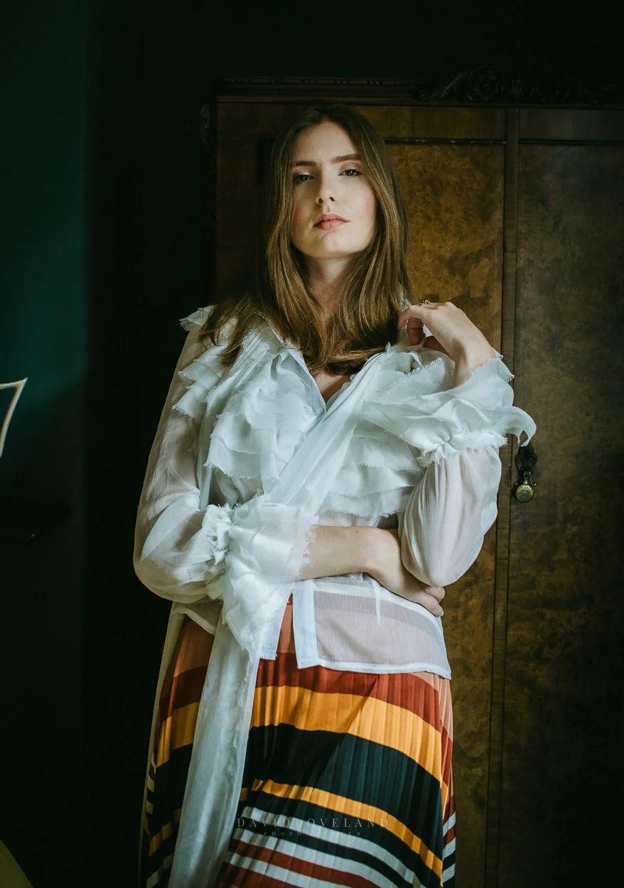 Tall fashion model wearing white ruffled vintage blouse and Zara pleated orange yellow striped skirt, fashion editorial photo shoot and styling by David Loveland Photography.  
