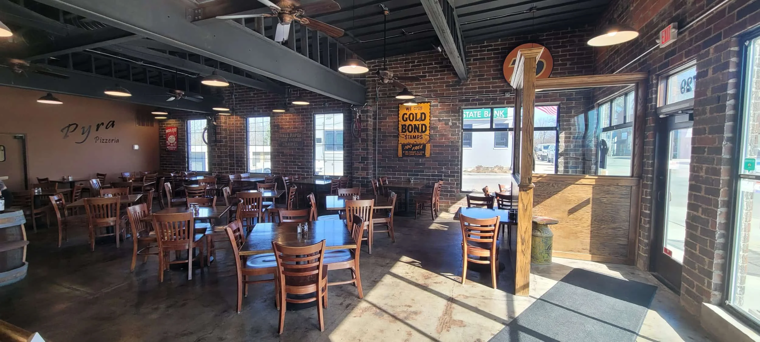 Sunlit pizzeria with brick walls, vintage signs, and large windows—easily checked off any commercial building inspection checklist.