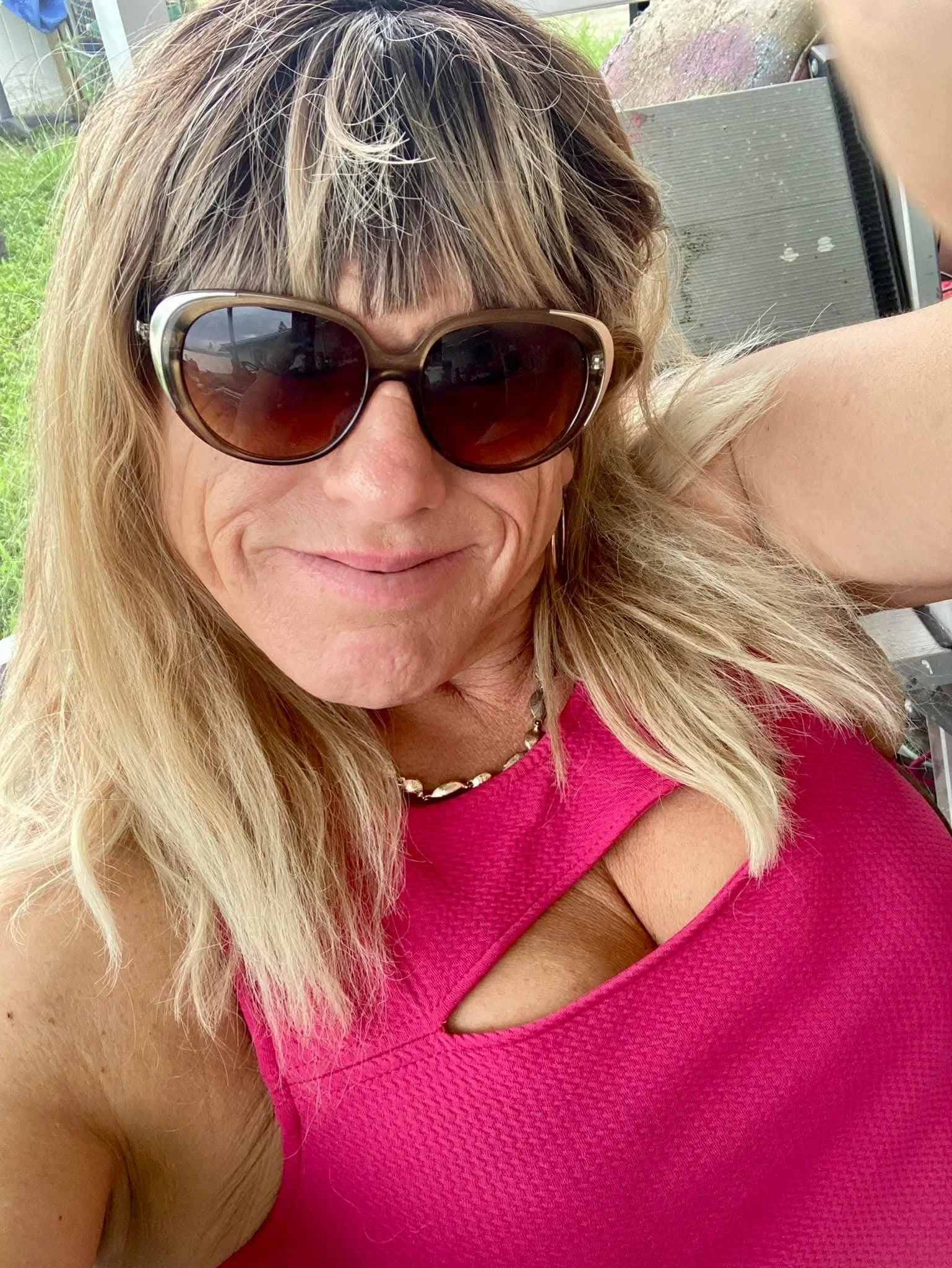 A smiling woman with brown hair in a ponytail holding a folder in an indoor office or modern workspace.