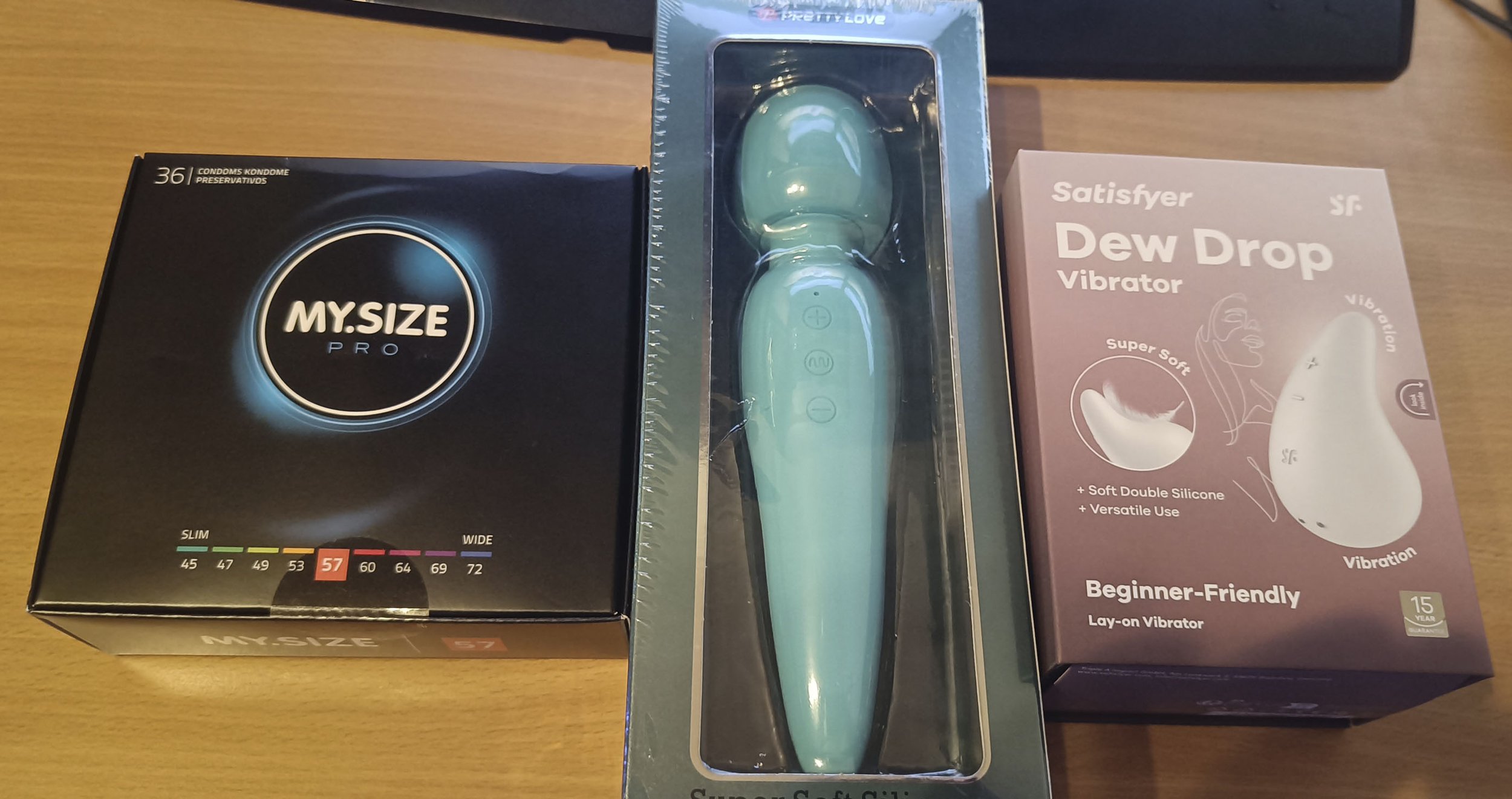 Vasemmalla laatikollinen kondomeja, keskellä sininen hieromasauva ja oikealla laatikossa valkoinen, pisaran mallinen vibraattori.