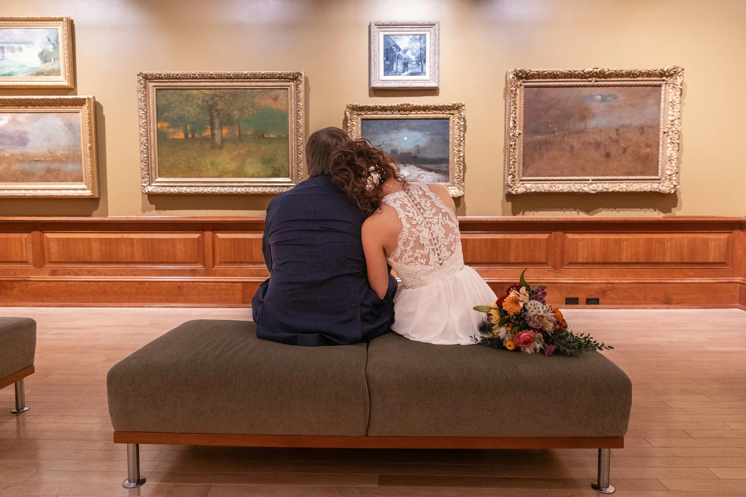 couple is sitting on the bench admiring art in the museum