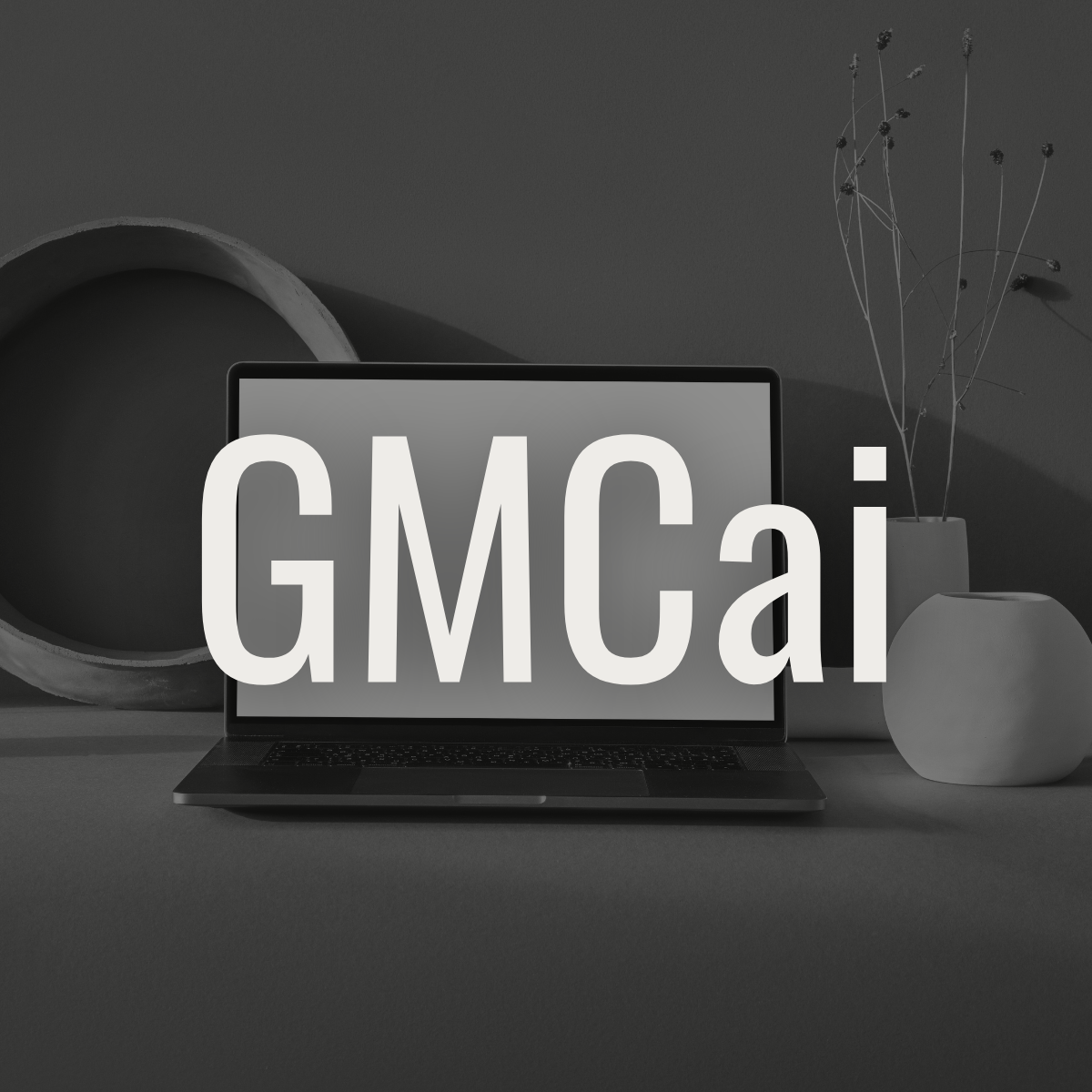 A laptop displaying the text 'GMC AI' on the screen, with decorative vases and dried flowers in the background, in a monochrome setup.