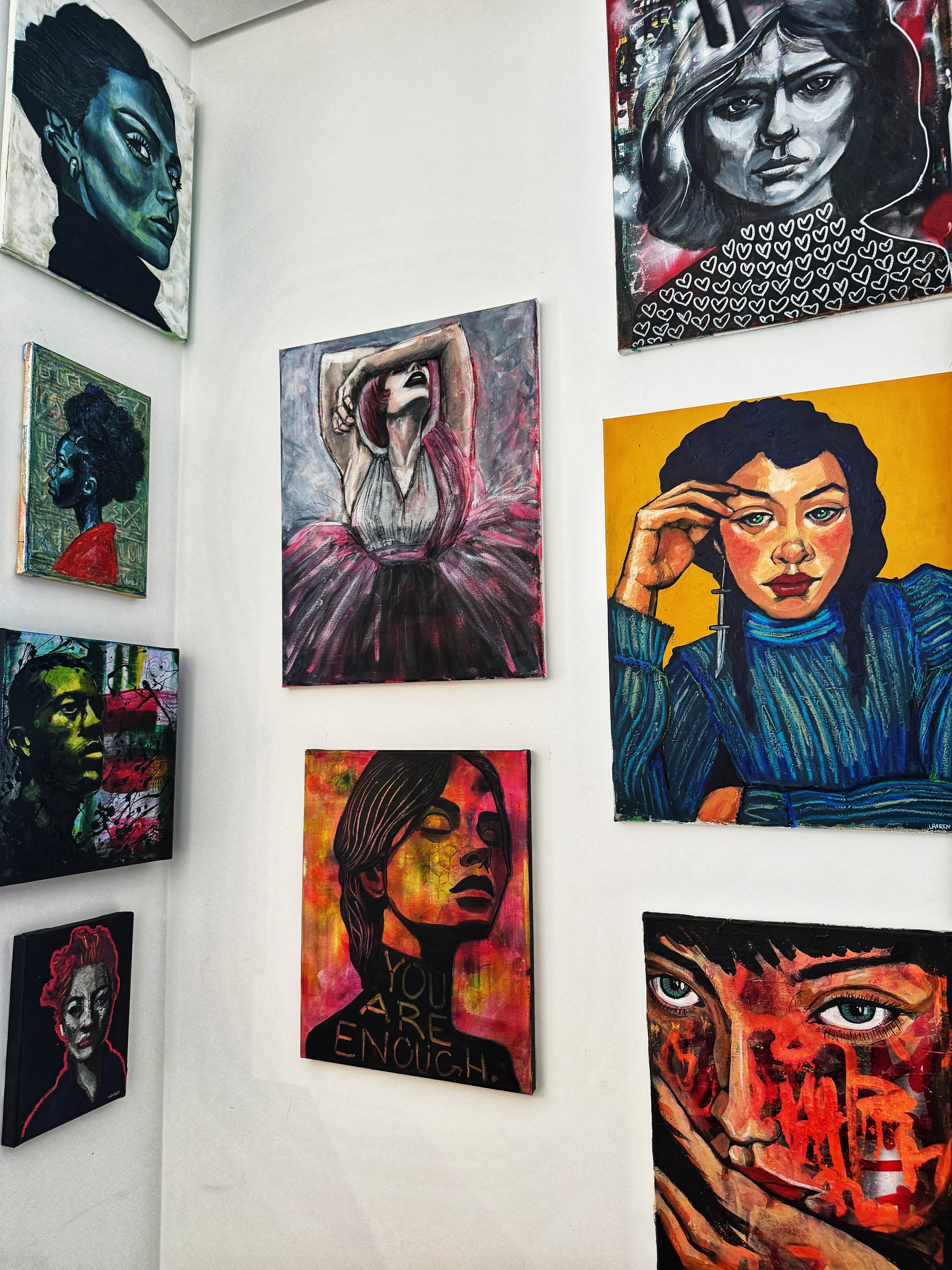 photo of a wall filled with original portrait paintings on canvas