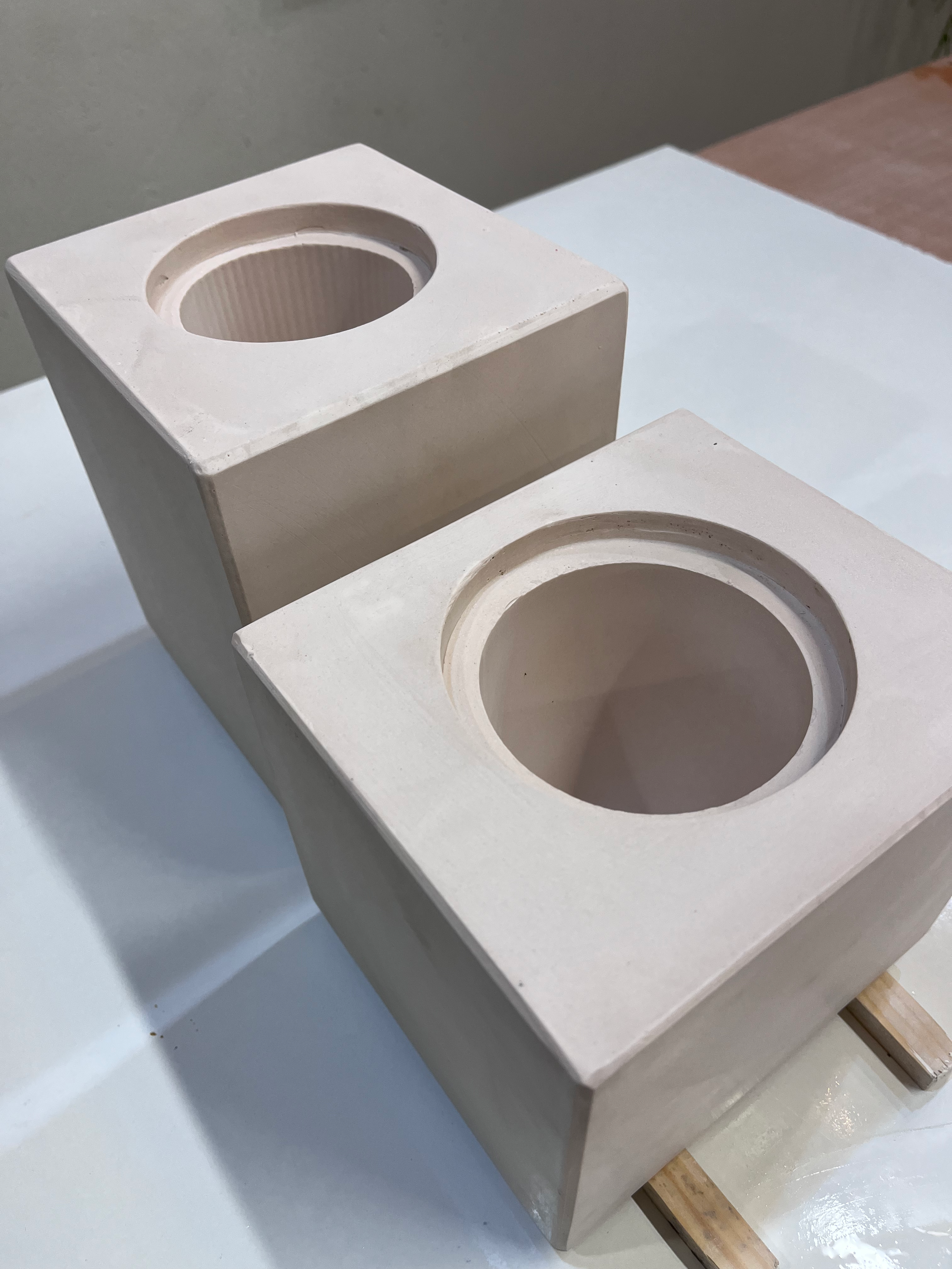 Examples from Plaster mould classes and workshops. Two white rectangular plaster moulds with circular openings on top, placed on a flat surface by Ceramic Artist and Tutor Andie Haycock in Tunbridge Wells Kent