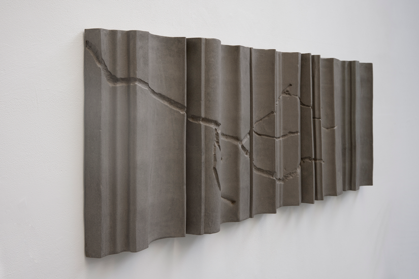 Concrete wall panel with a crack and a wavy, corrugated design.