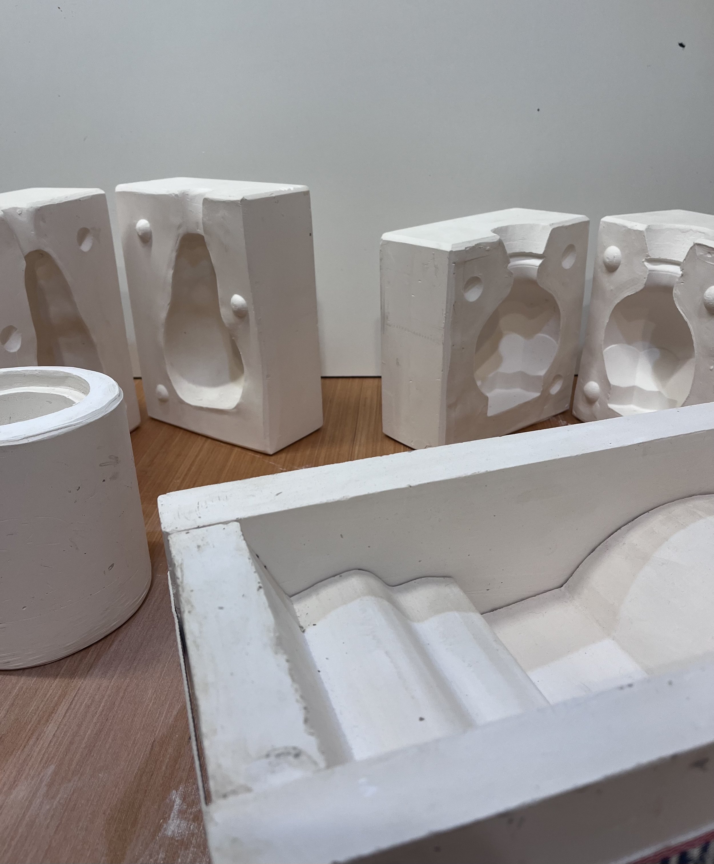 White plaster molds and casting forms arranged on a wooden surface.