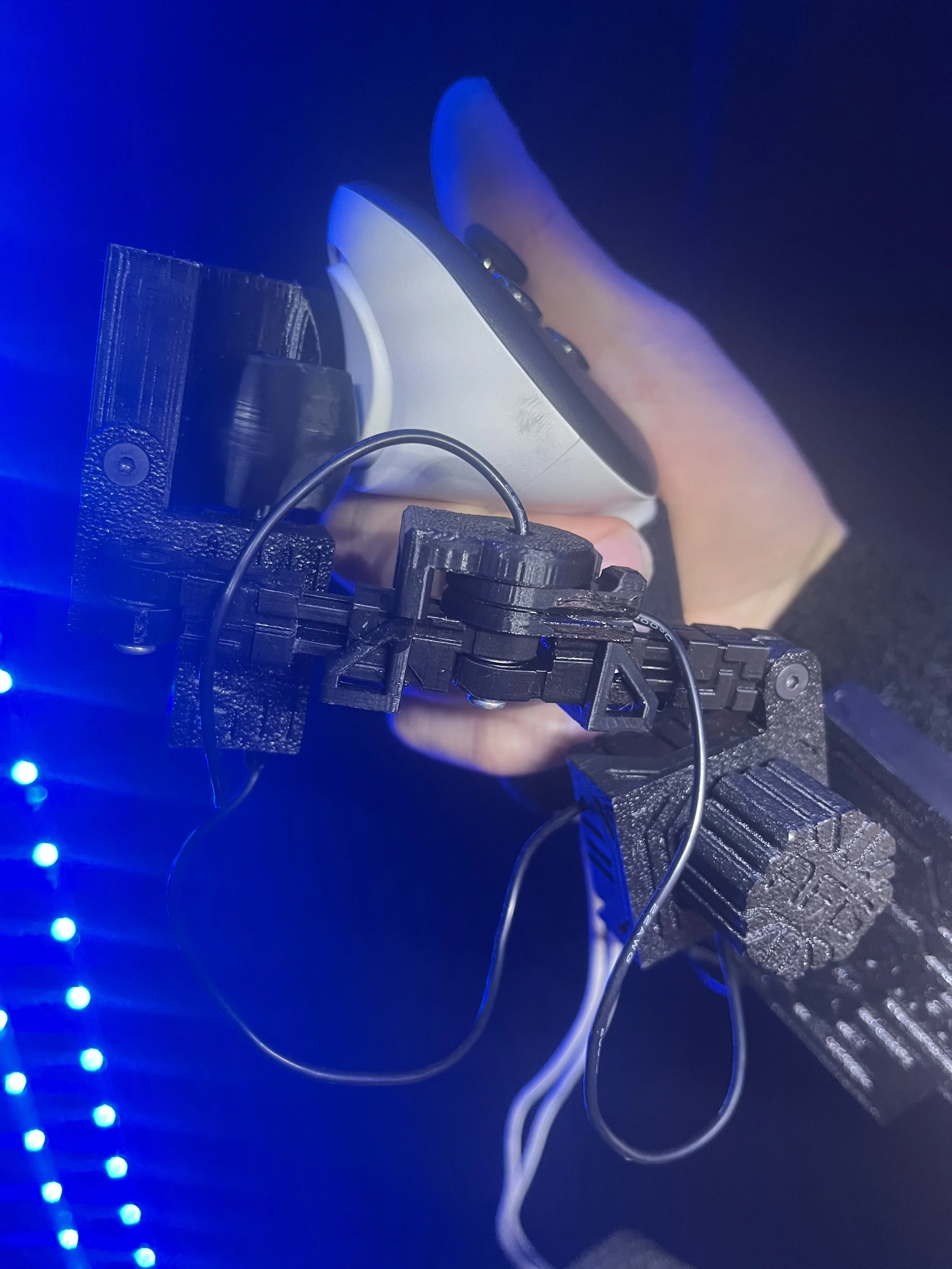 A robotic arm holding a gaming controller, with blue LED lighting and a dark background.