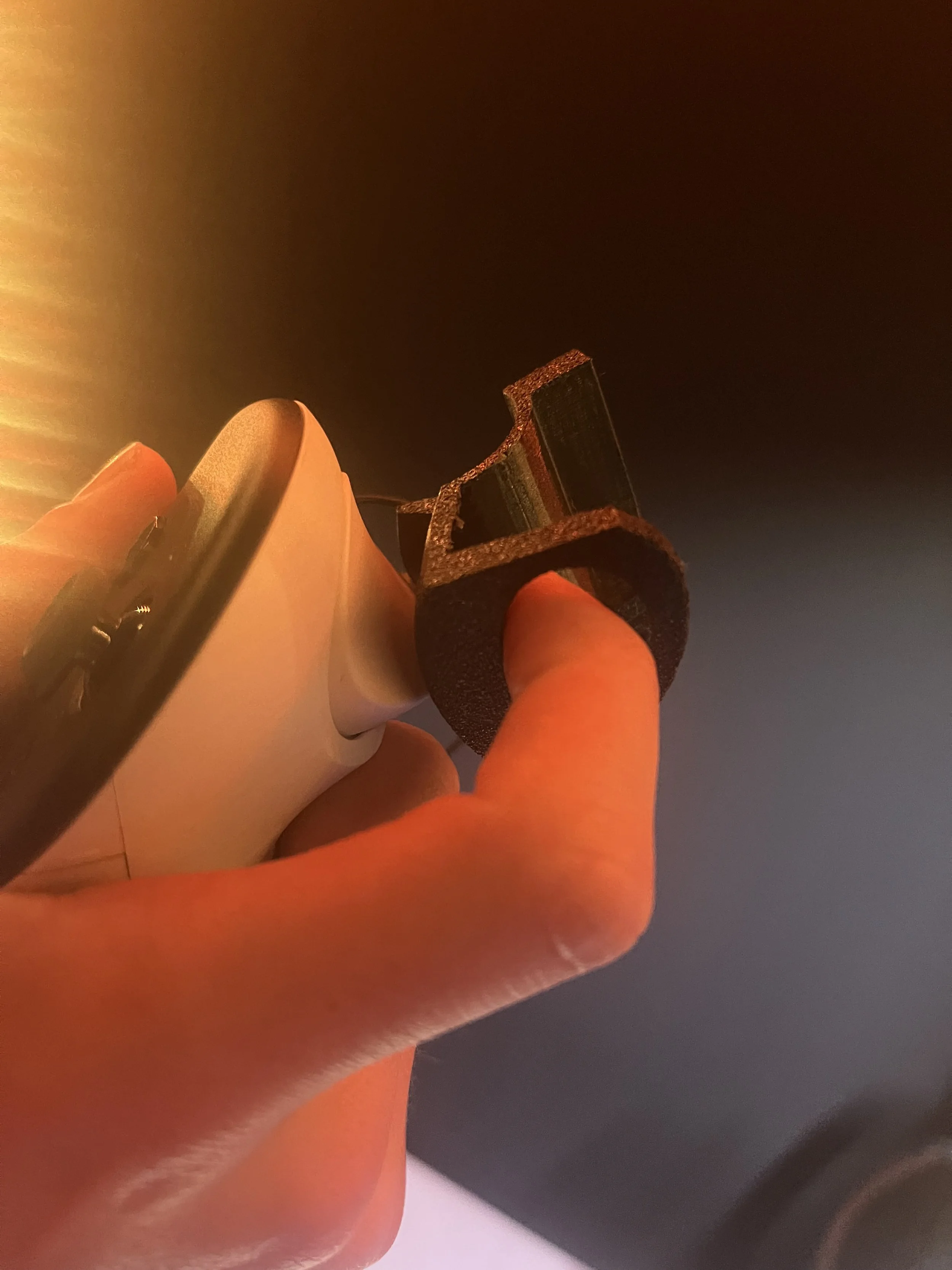 Close-up of a person's fingers holding a plug near an electrical outlet, with warm lighting.