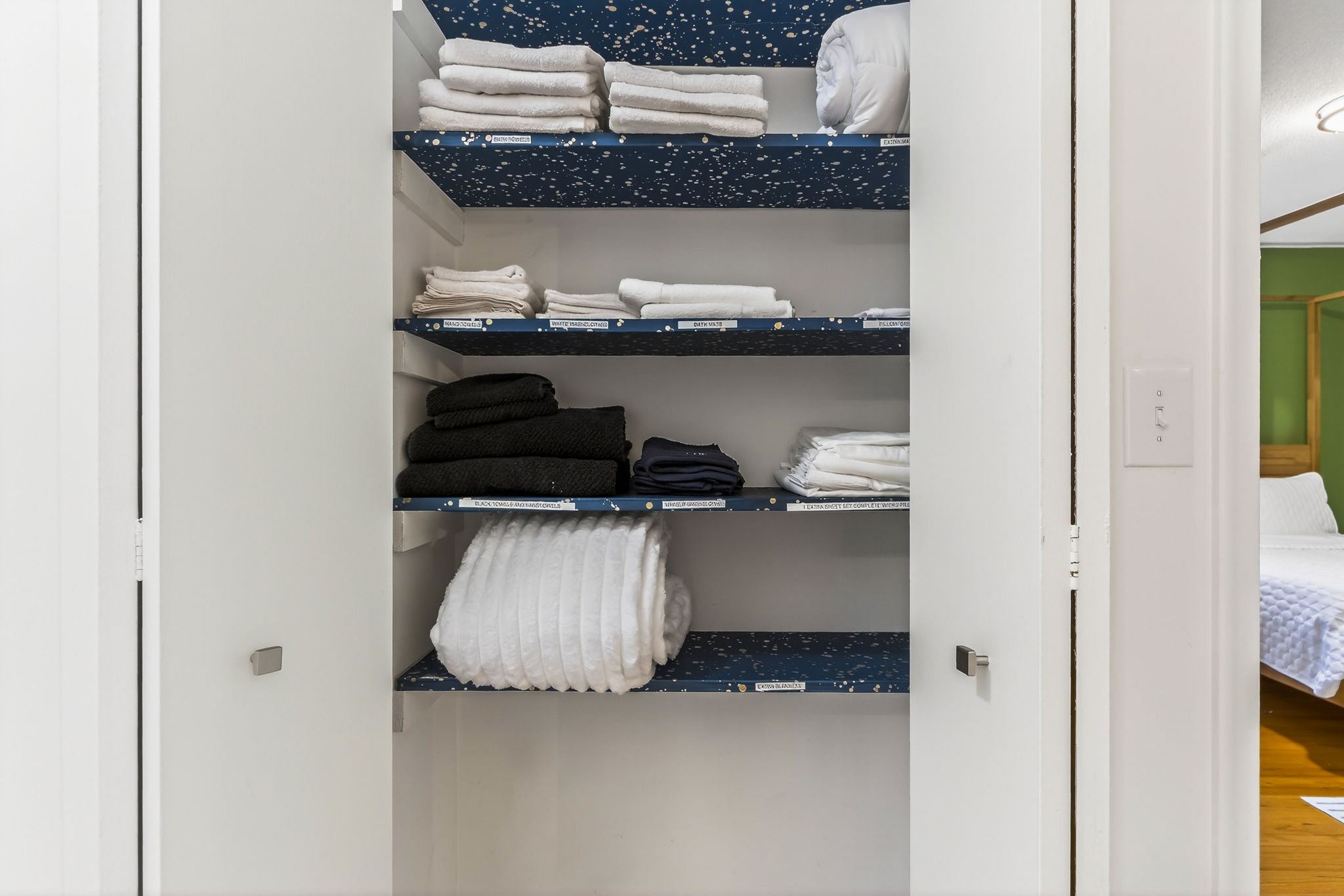 Shelves with folded towels, cloths, and bedding in a closet.
