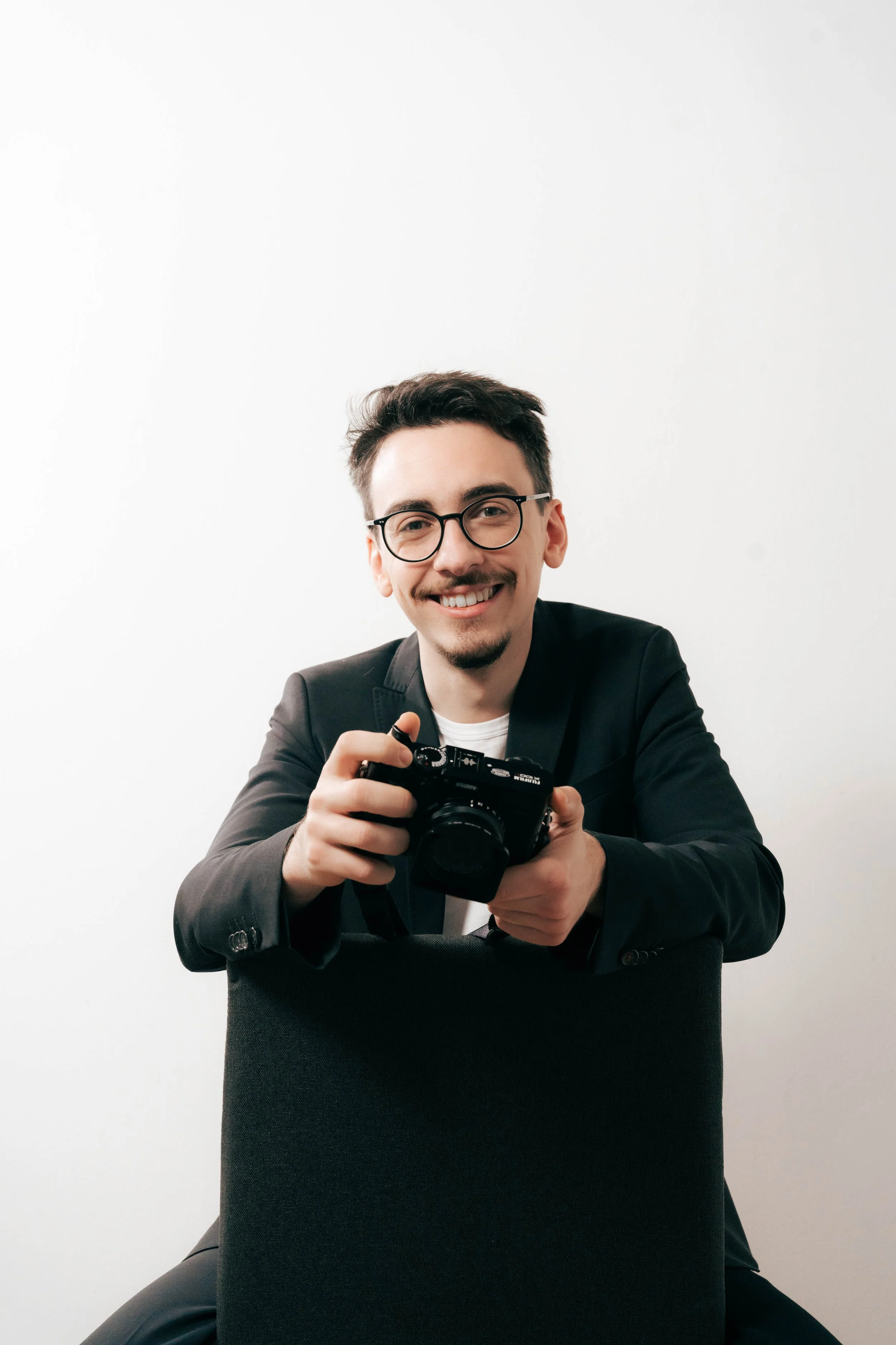 Fabian Hasler, ein Grazer Fotograf und Filmemacher im Porträt mit einer kleinen Fujifilm Kamera in der Hand.