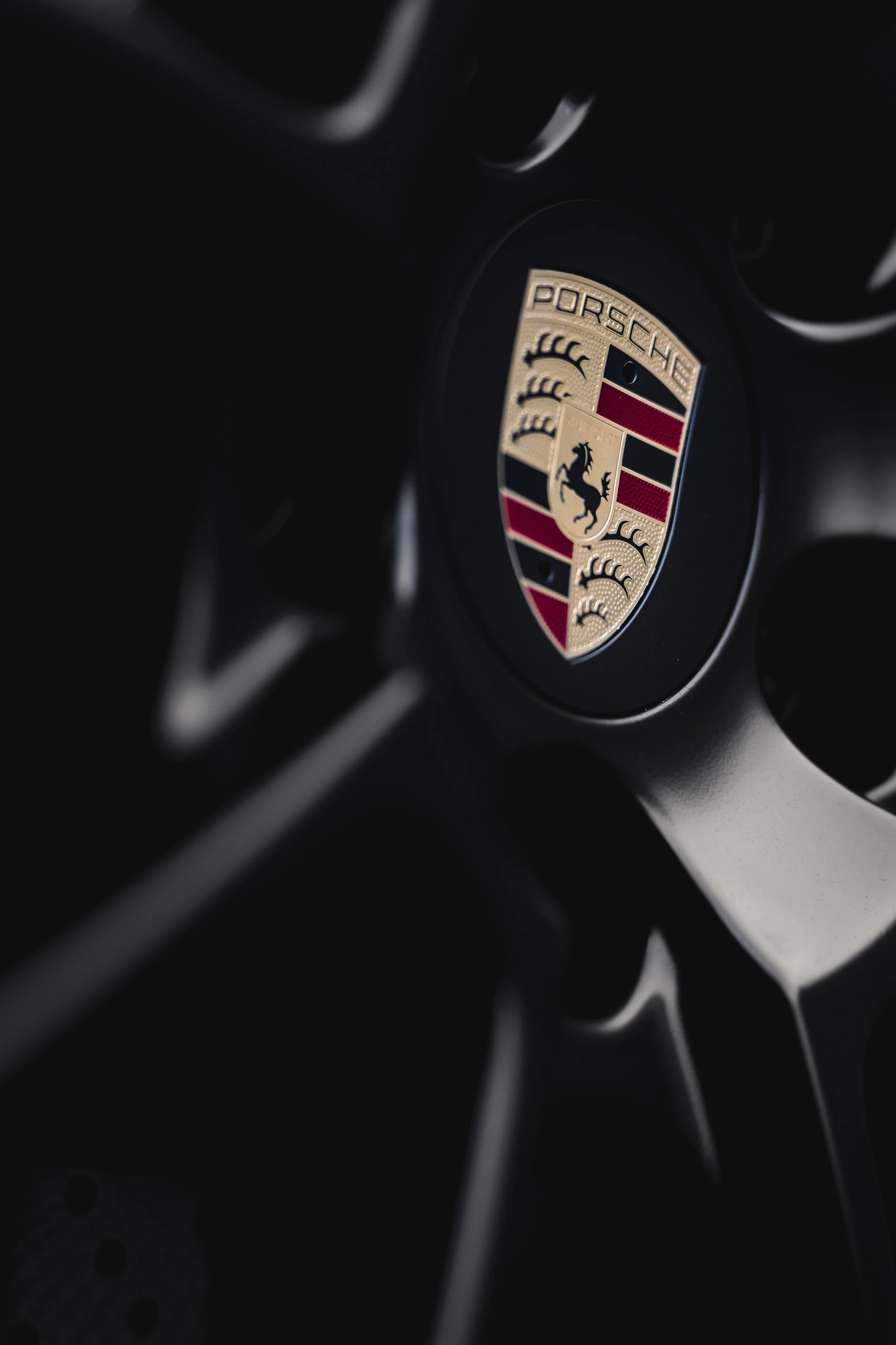 Nahaufnahme des Porsche-Logos auf einem Fahrzeuglenkrad.