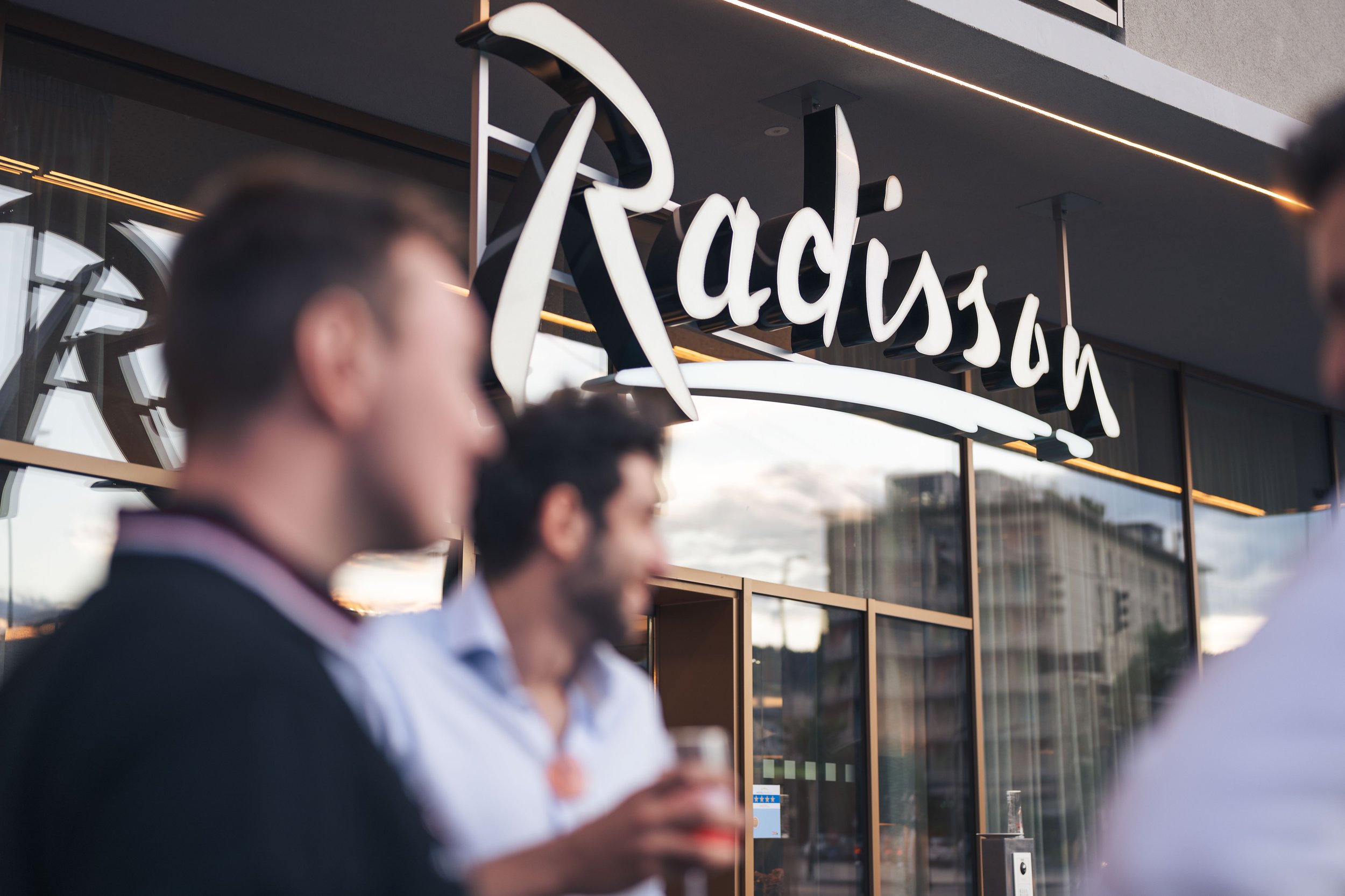 Menschen vor einem Café namens 'Radiation', das eine moderne Fassade mit großen Fenstern hat.
