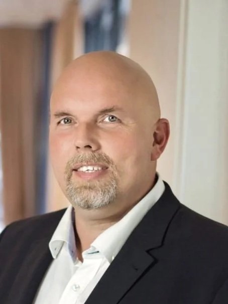 Ein Mann in formeller Kleidung vor einem Bücherregal