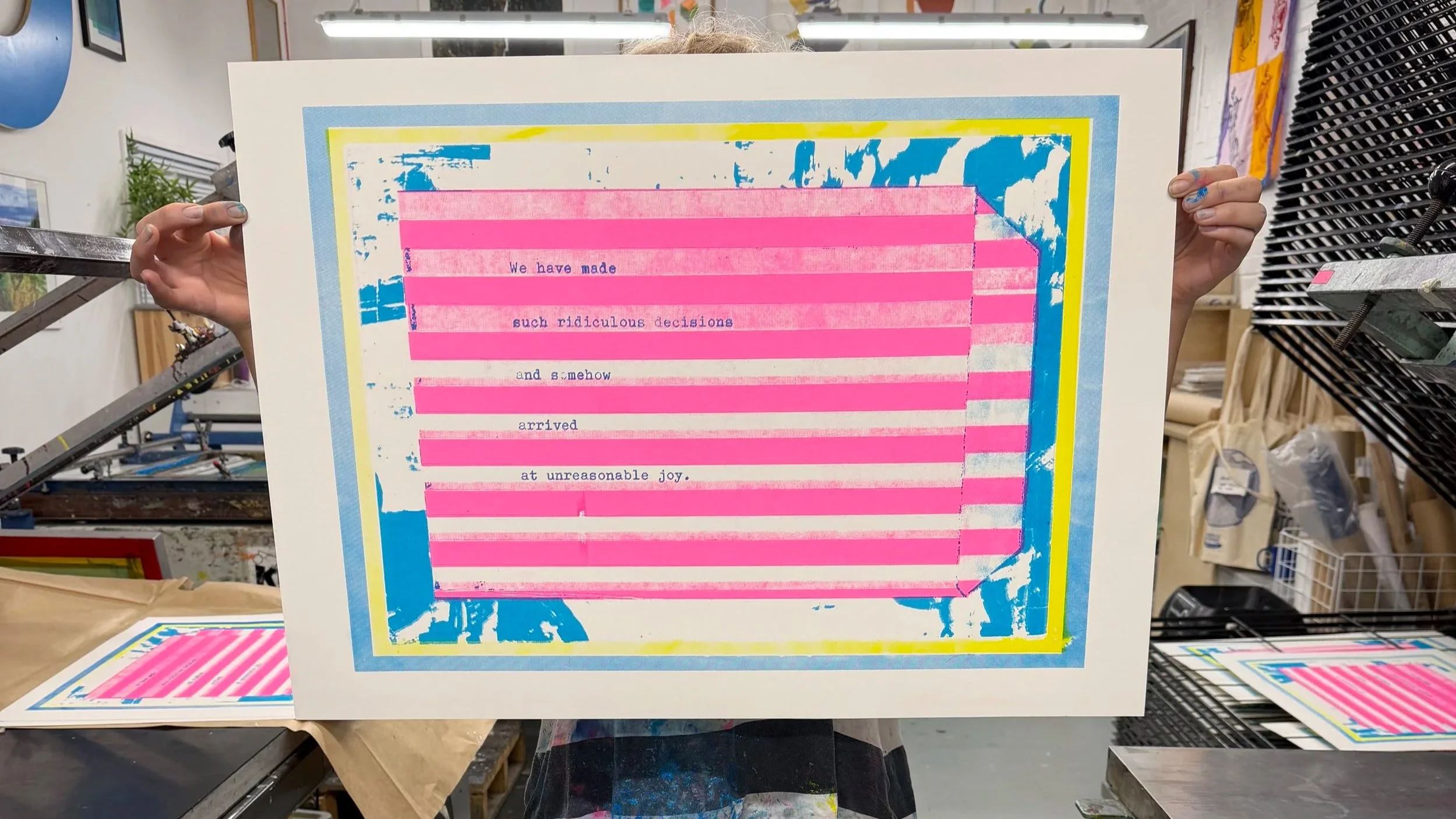 Person holding a colorful abstract artwork with pink lines and blue and yellow accents, with text about decisions and joy.