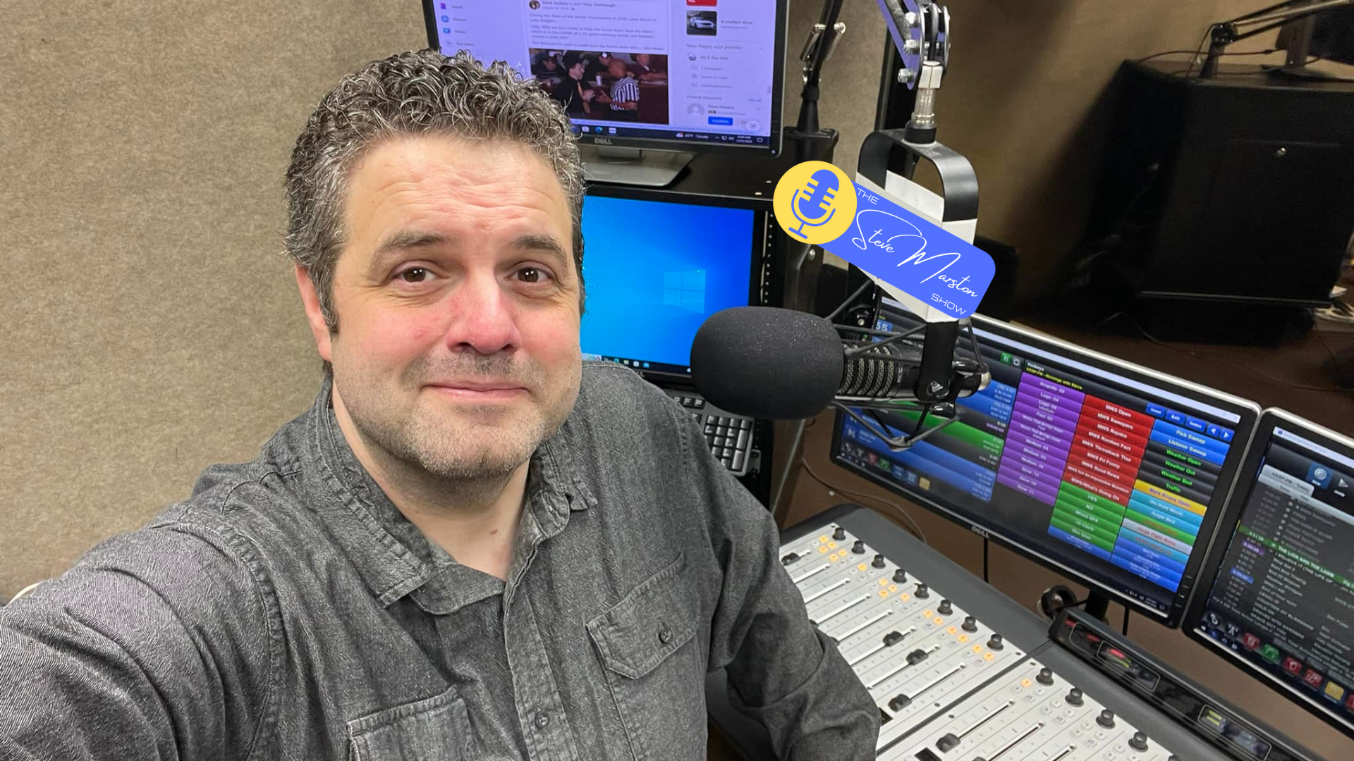 A man taking a selfie in a radio studio, surrounded by broadcasting equipment, including microphones, monitors, and a soundboard with colorful controls. A sticker on the microphone reads 'The Steve Maston Show'.