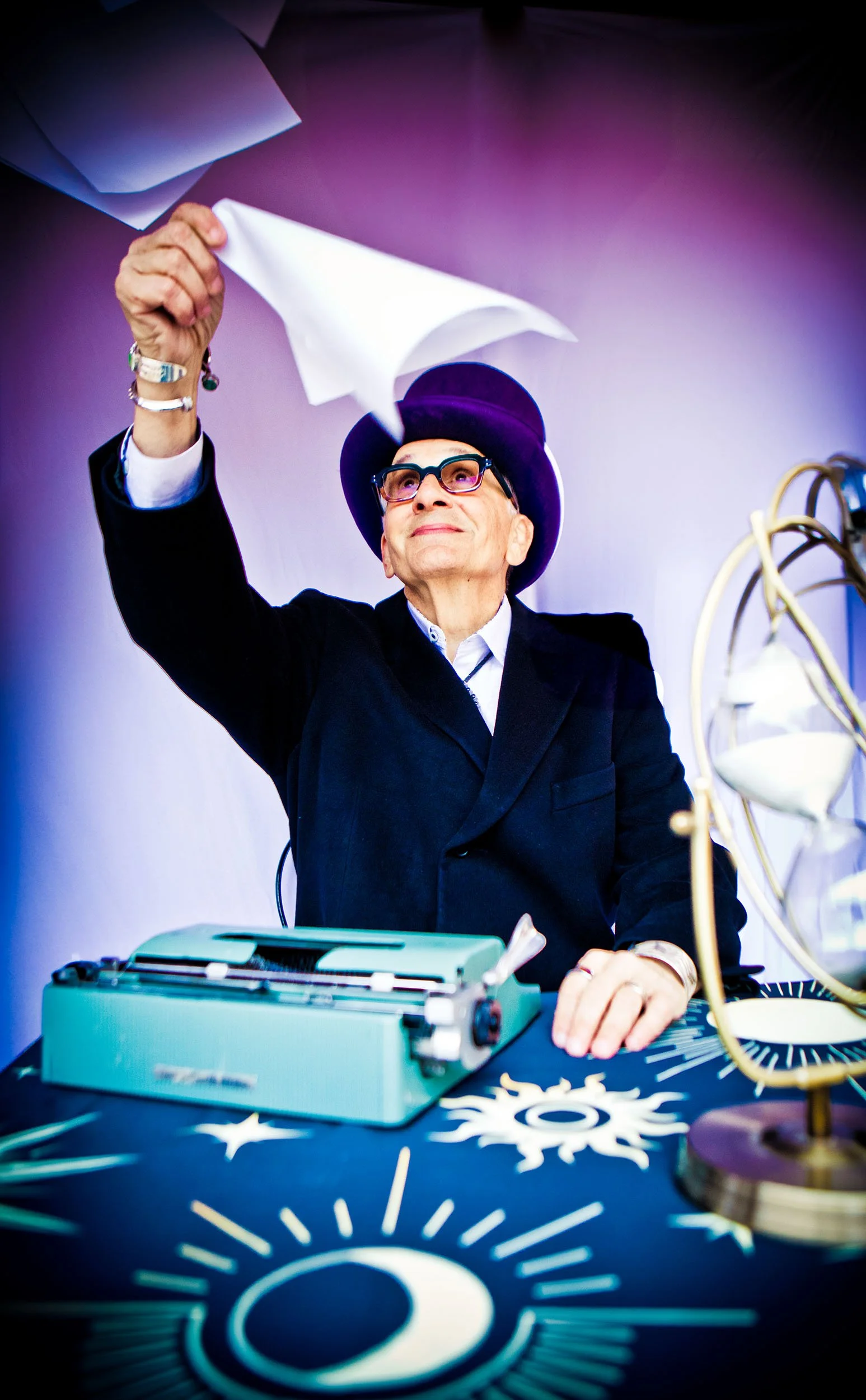 The Great Zandini wearing purple felt top hat throwing papers out of a typewriter