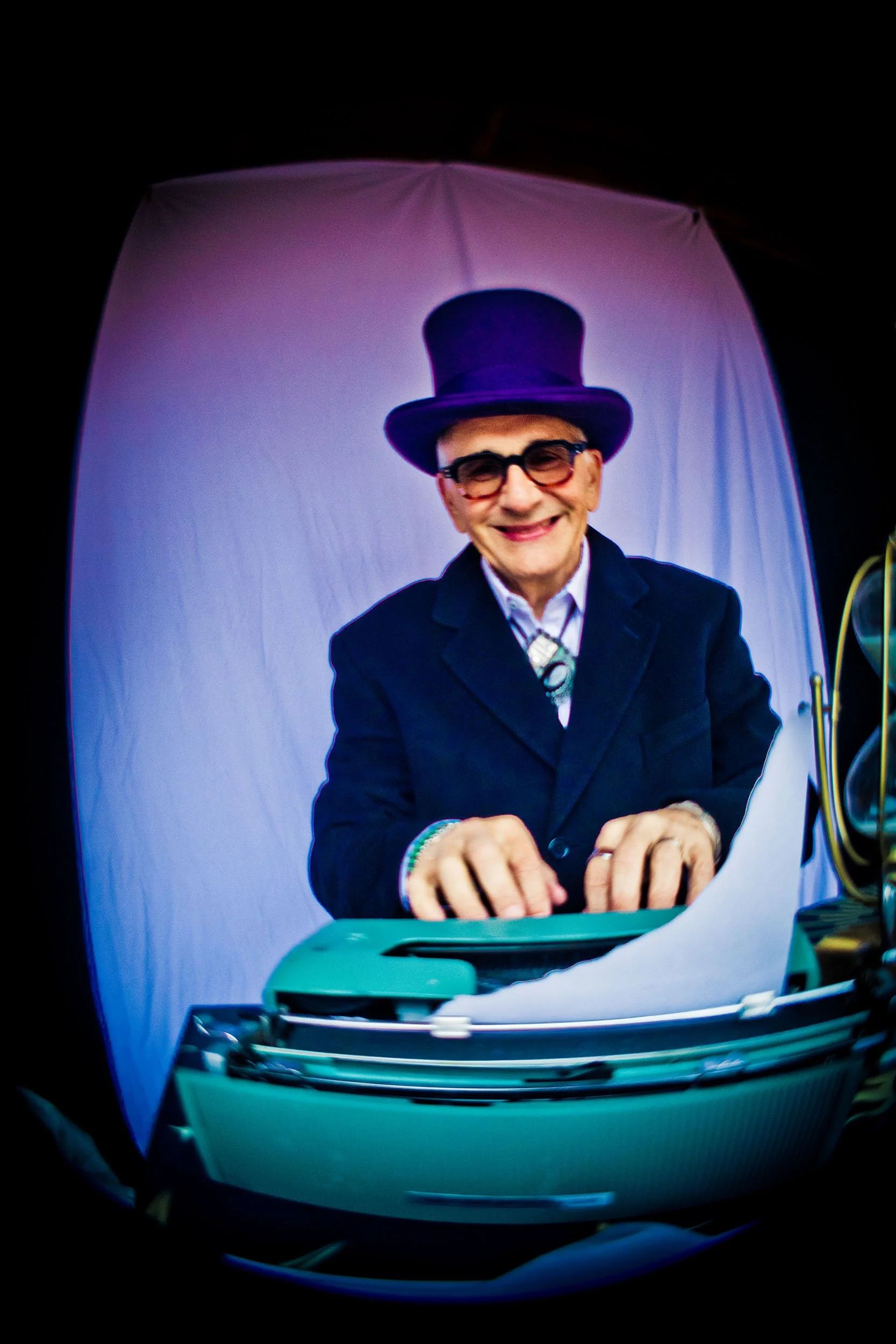 The Great Zandini wearing purple top hat and coat typing on green typewriter