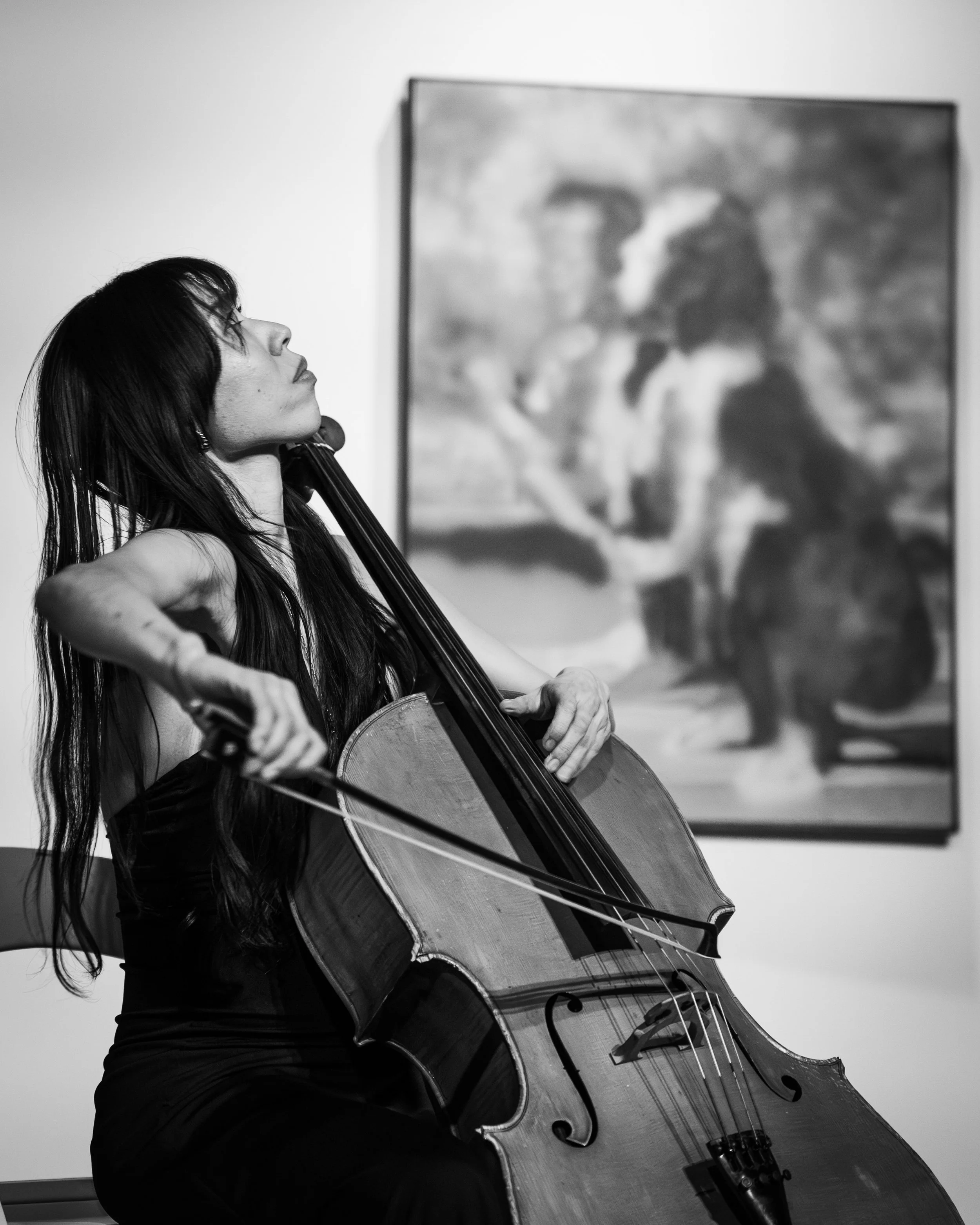 A woman playing a cello in an art gallery.
