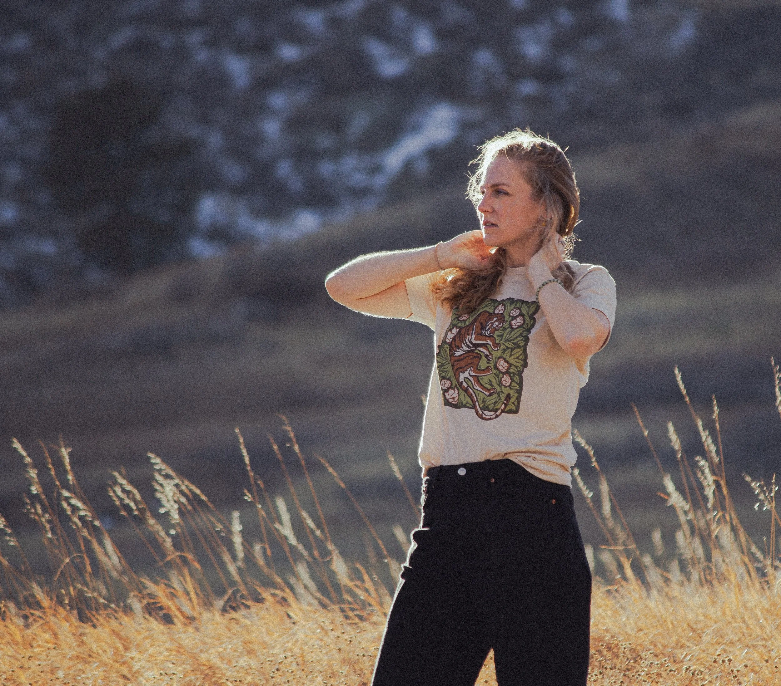 A lifestyle photo of a woman wearing the shirt standing in a field of wheat